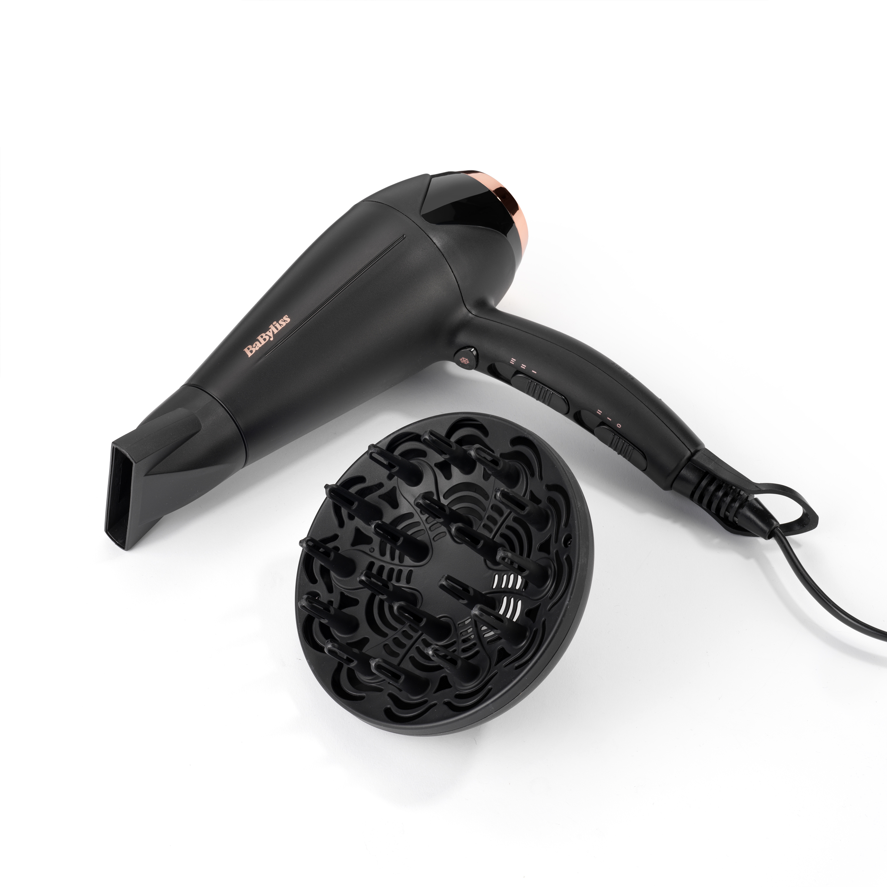 Secador de pelo negro con boquilla y difusor, todo sobre una superficie blanca.