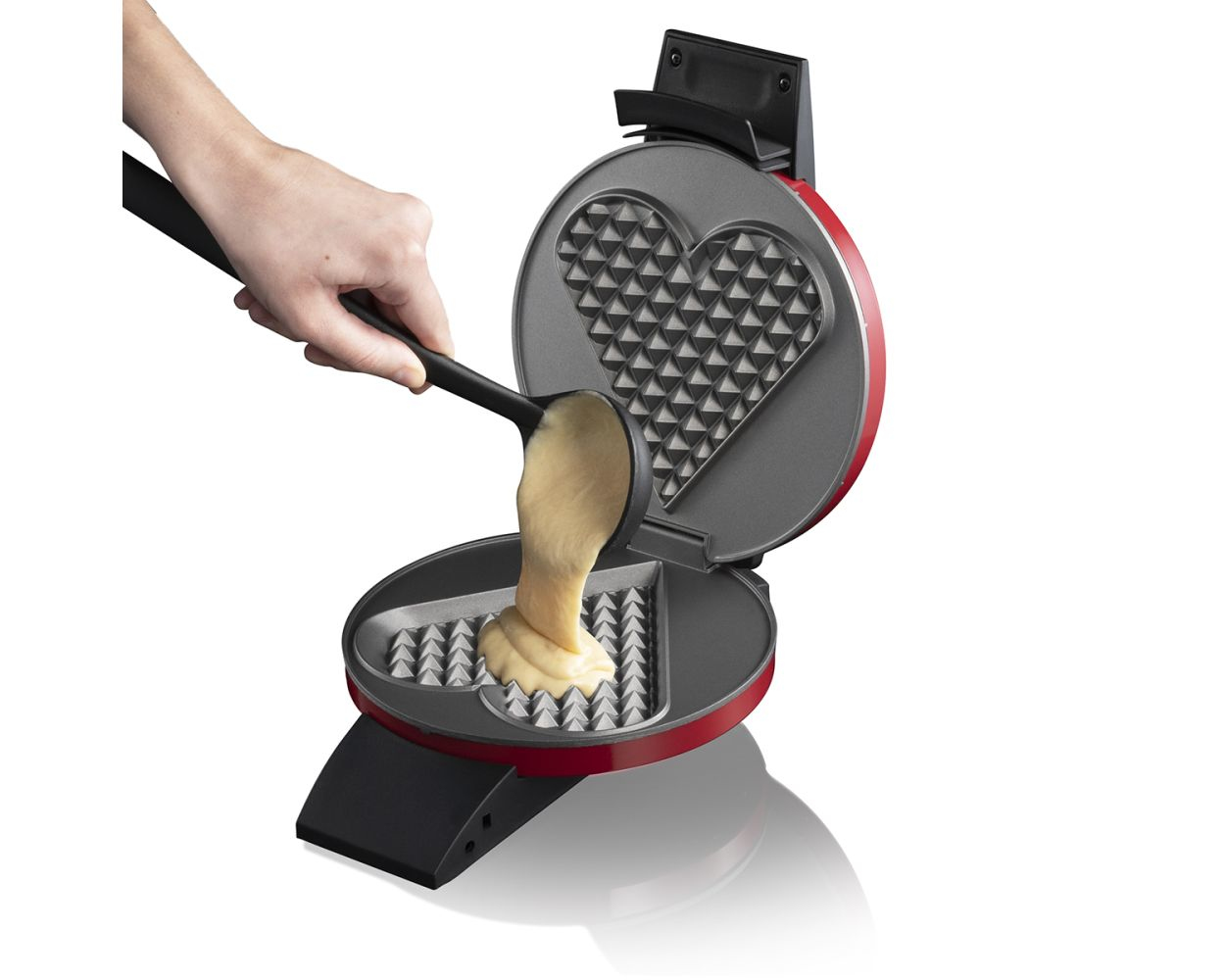 Czerwone gofrownica z formami w kształcie serca, wlewanie ciasta.