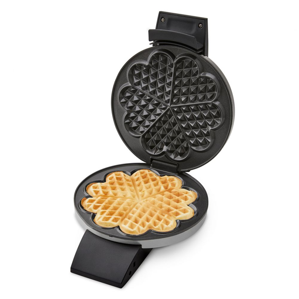 Otwarta gofrownica z upieczonym gofrem w kształcie serca. Jest na białym tle.