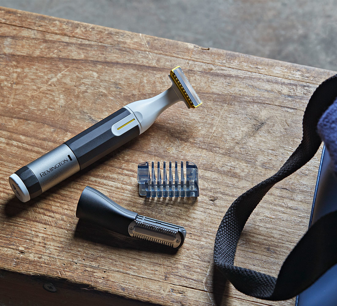 Ein Remington Trimmer und Aufsätze auf einer Holzoberfläche. Teile umfassen einen Trimmer, Klingen und einen weiteren Aufsatz.