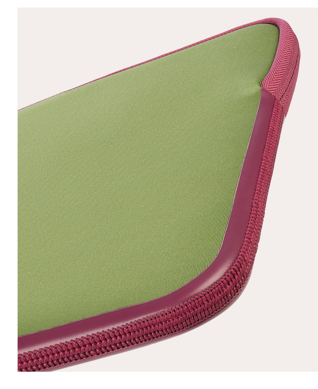 Primo piano di un cuscino verde oliva con bordo magenta. Il bordo ha una trama intrecciata.
