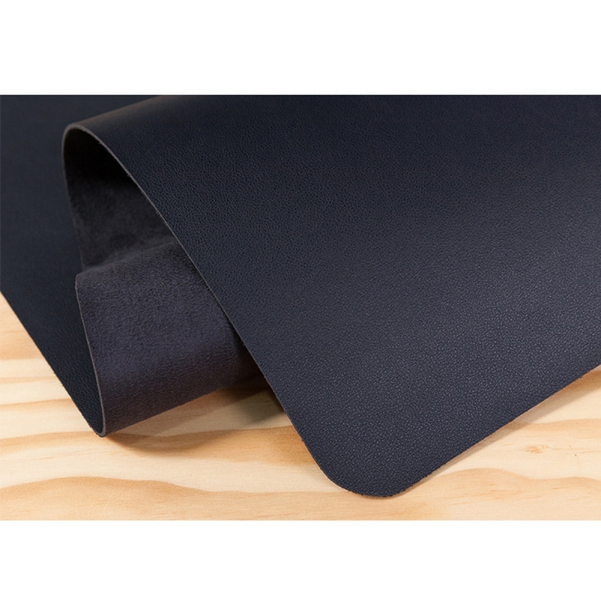Foglio di pelle blu scuro su assi di legno, trama visibile, superficie liscia.