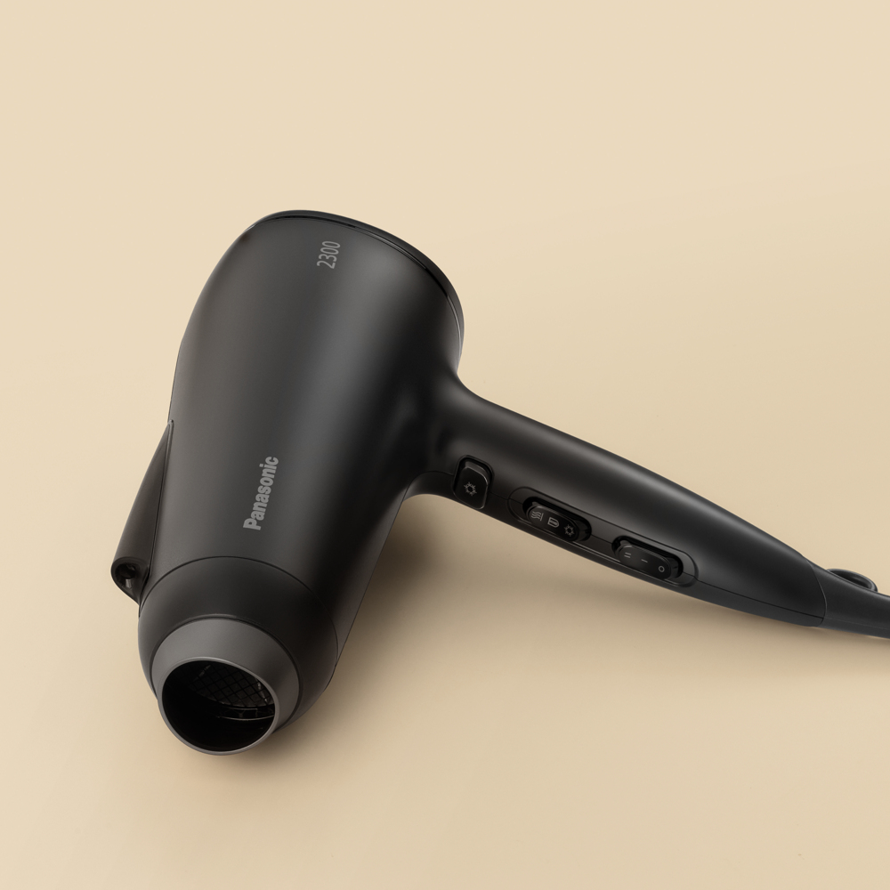Czarna suszarka do włosów Panasonic na beżowym tle.