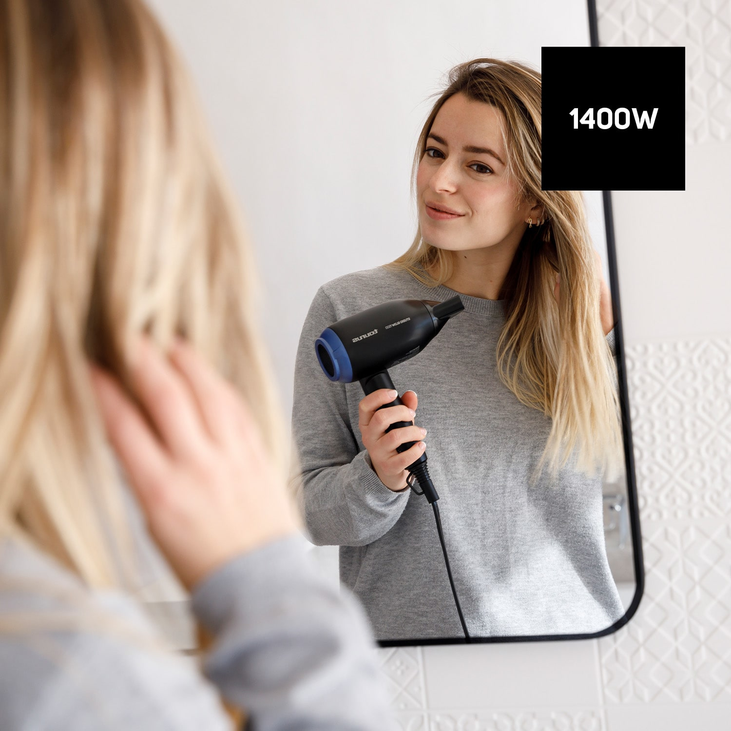 Kobieta używająca czarnej suszarki do włosów przed lustrem. Pole tekstowe 1400W znajduje się w prawym górnym rogu.