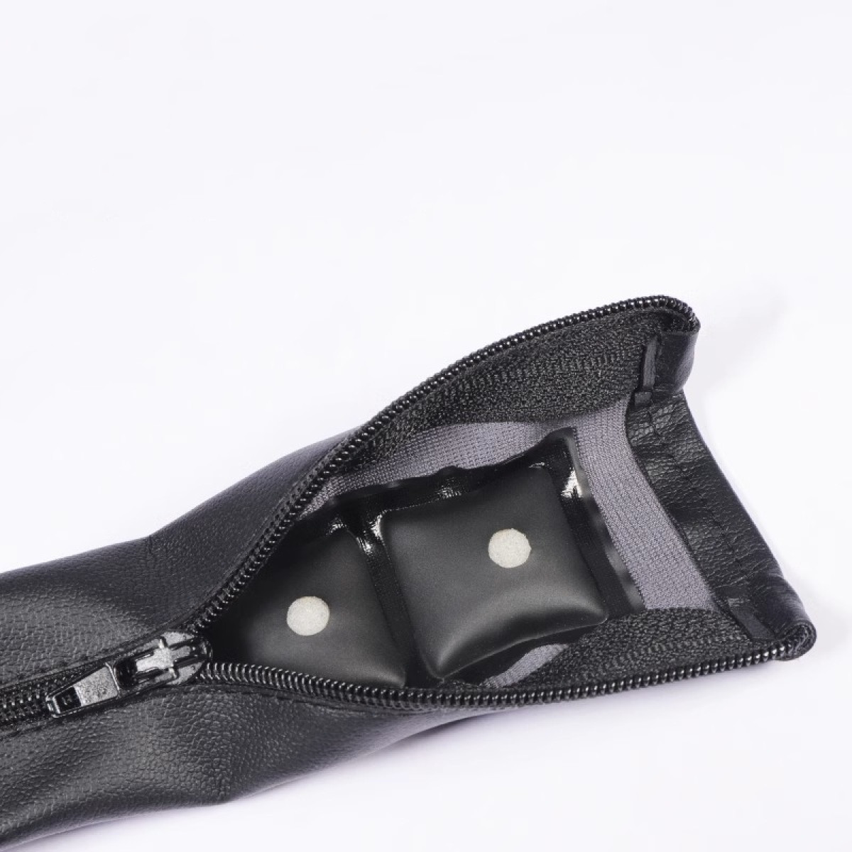 Custodia nera con zip aperta, rivela due piccoli cuscini quadrati neri con puntini bianchi.