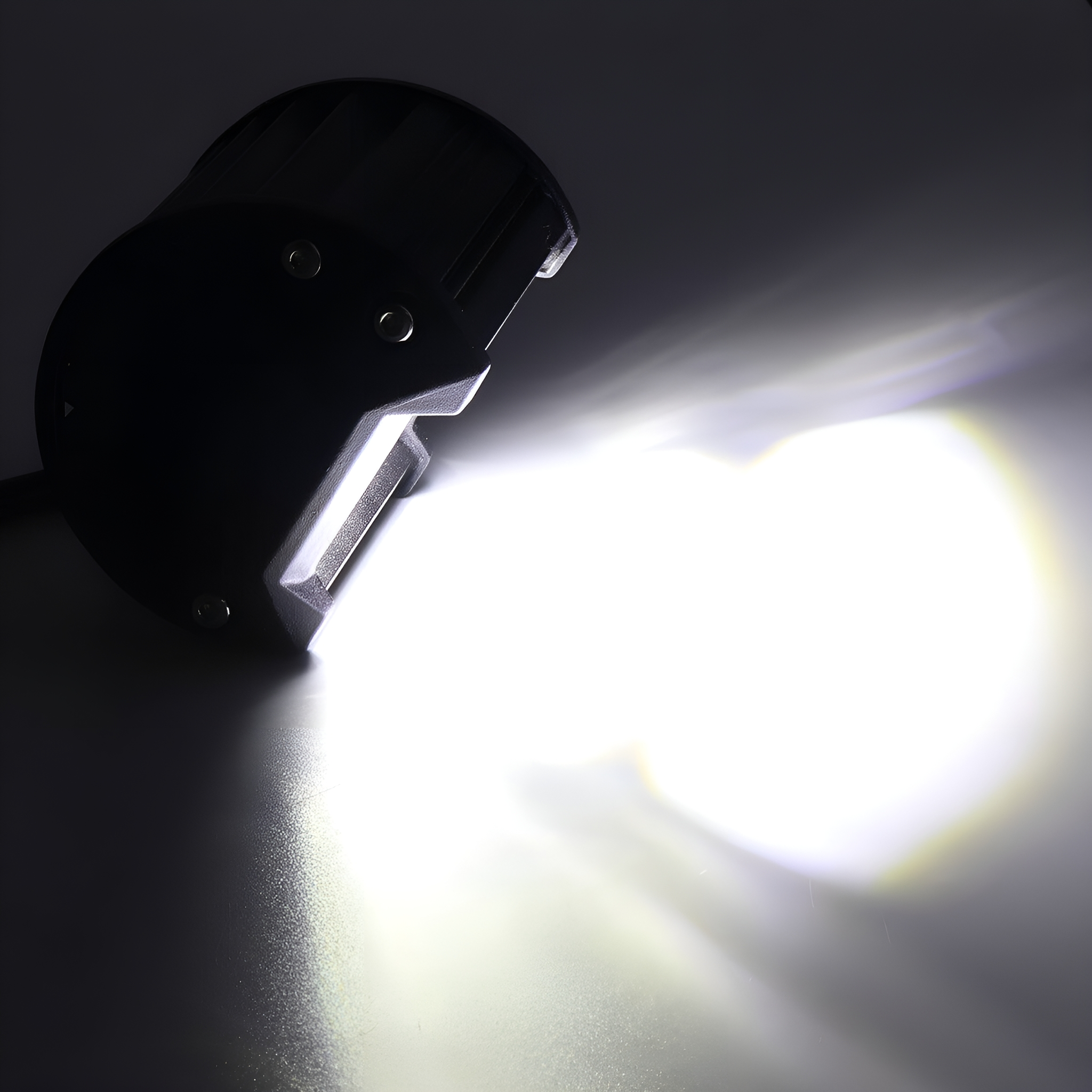 Schwarzes LED-Licht mit einem hellen, konzentrierten Lichtstrahl auf grauer Oberfläche.