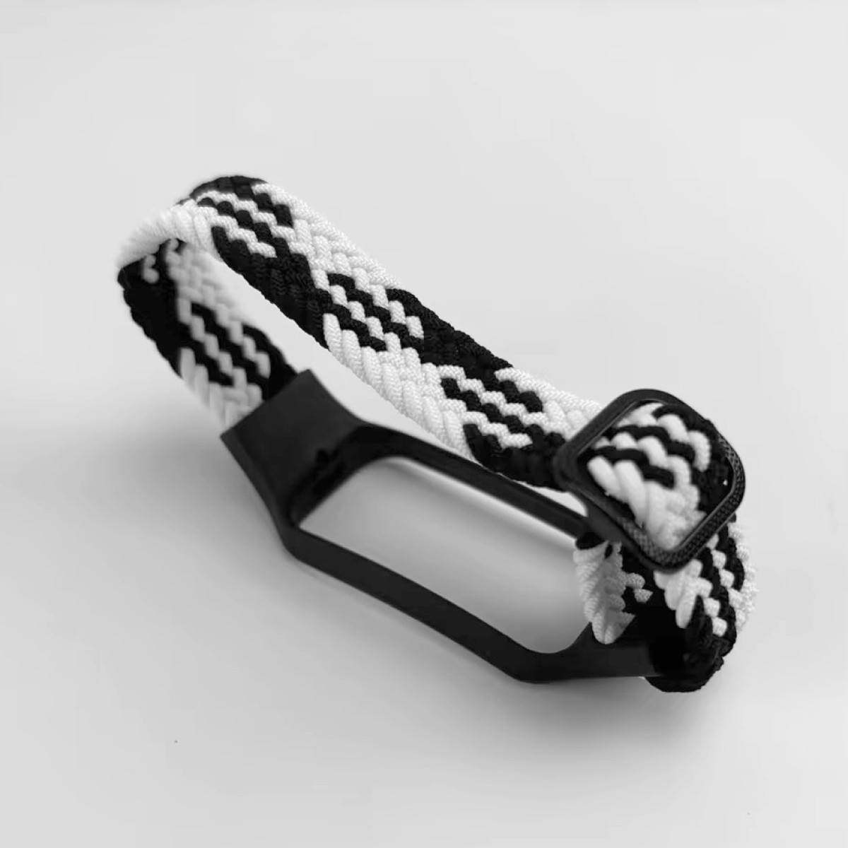 Ein schwarz-weiß geflochtenes Uhrenarmband mit schwarzer Kunststoffbasis und Schnalle.