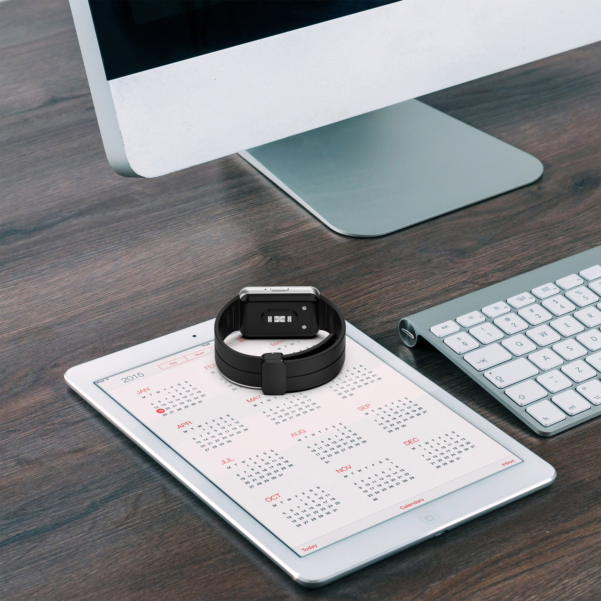 Smartwatch auf Tablet mit Kalender. Tastatur und Computermonitor sind ebenfalls vorhanden.