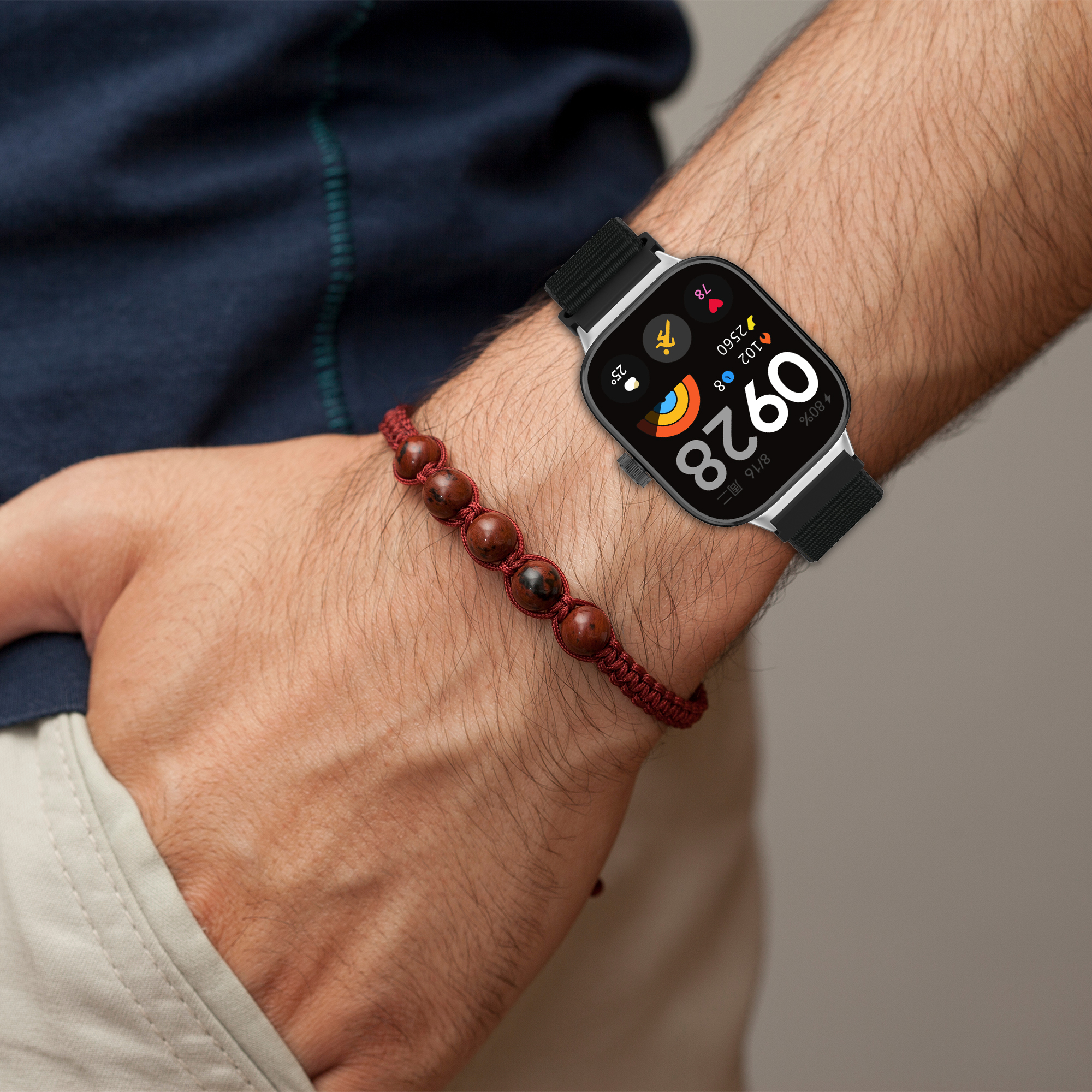 Mann trägt Smartwatch und rotes Armband, Arm-Nahaufnahme.
