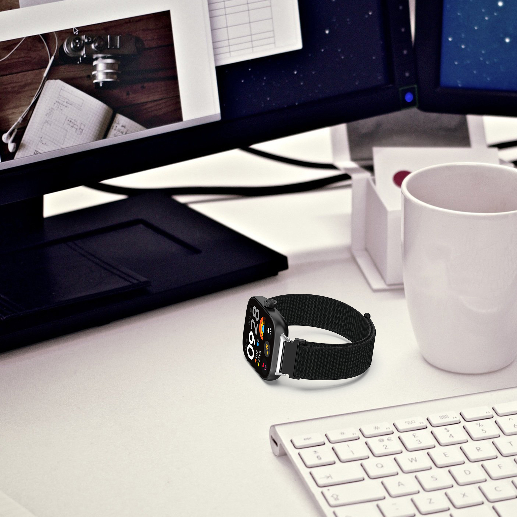 Smartwatch auf einem Schreibtisch mit Tastatur und Monitor. Die Uhr zeigt die Zeit an.