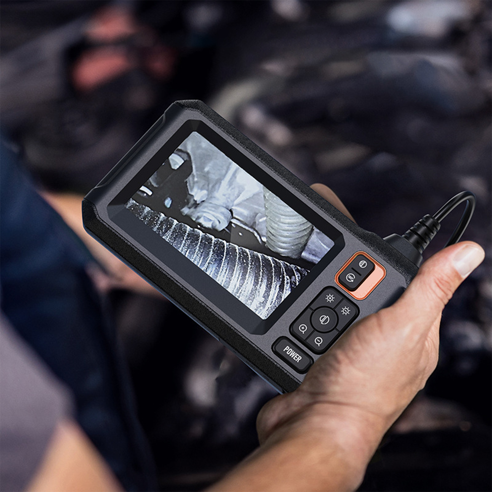 Hand, die ein Gerät hält, das ein Bild im Motor eines Autos zeigt.