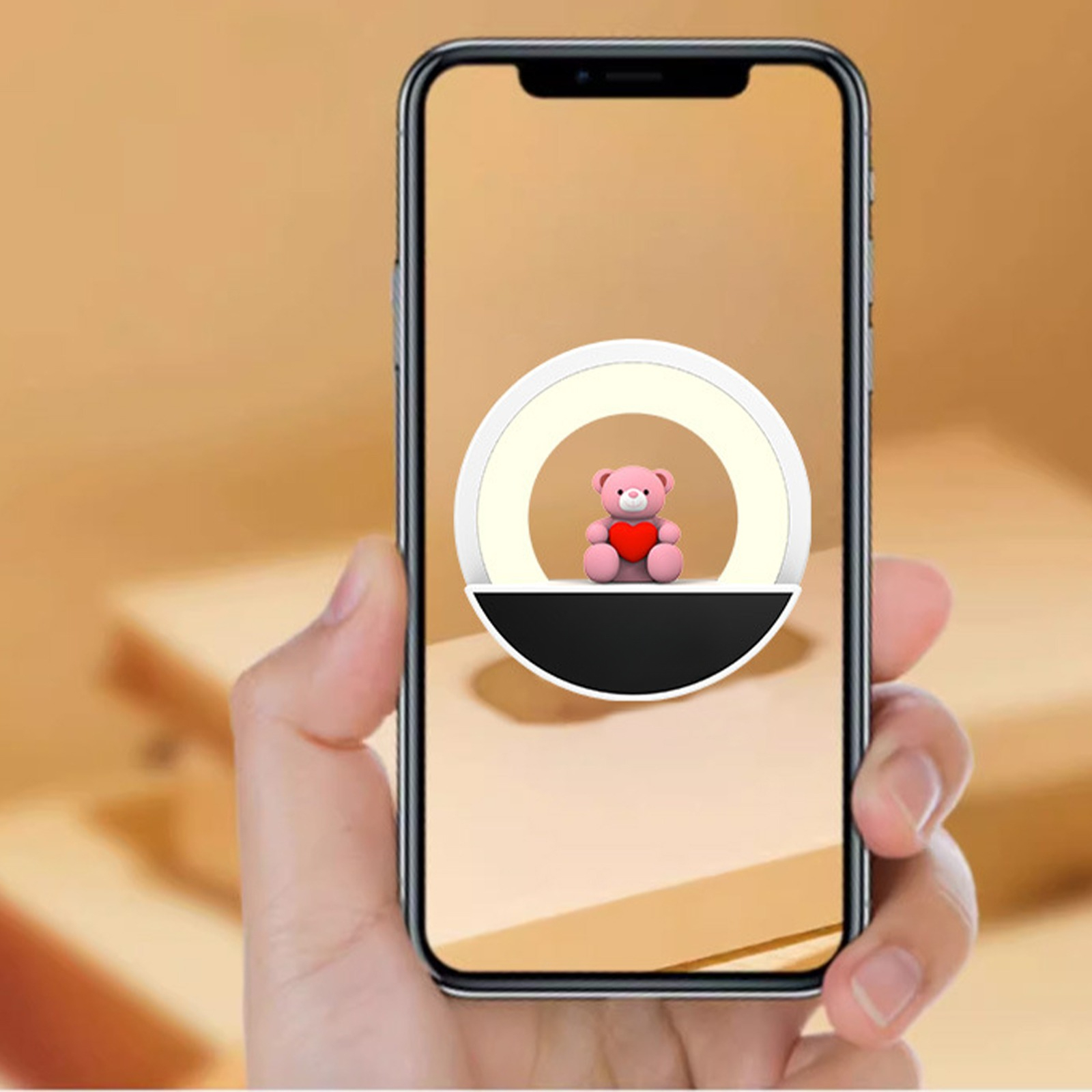 Eine Hand, die ein Telefon hält, zeigt ein Ringlicht und einen Teddybären mit Herz.