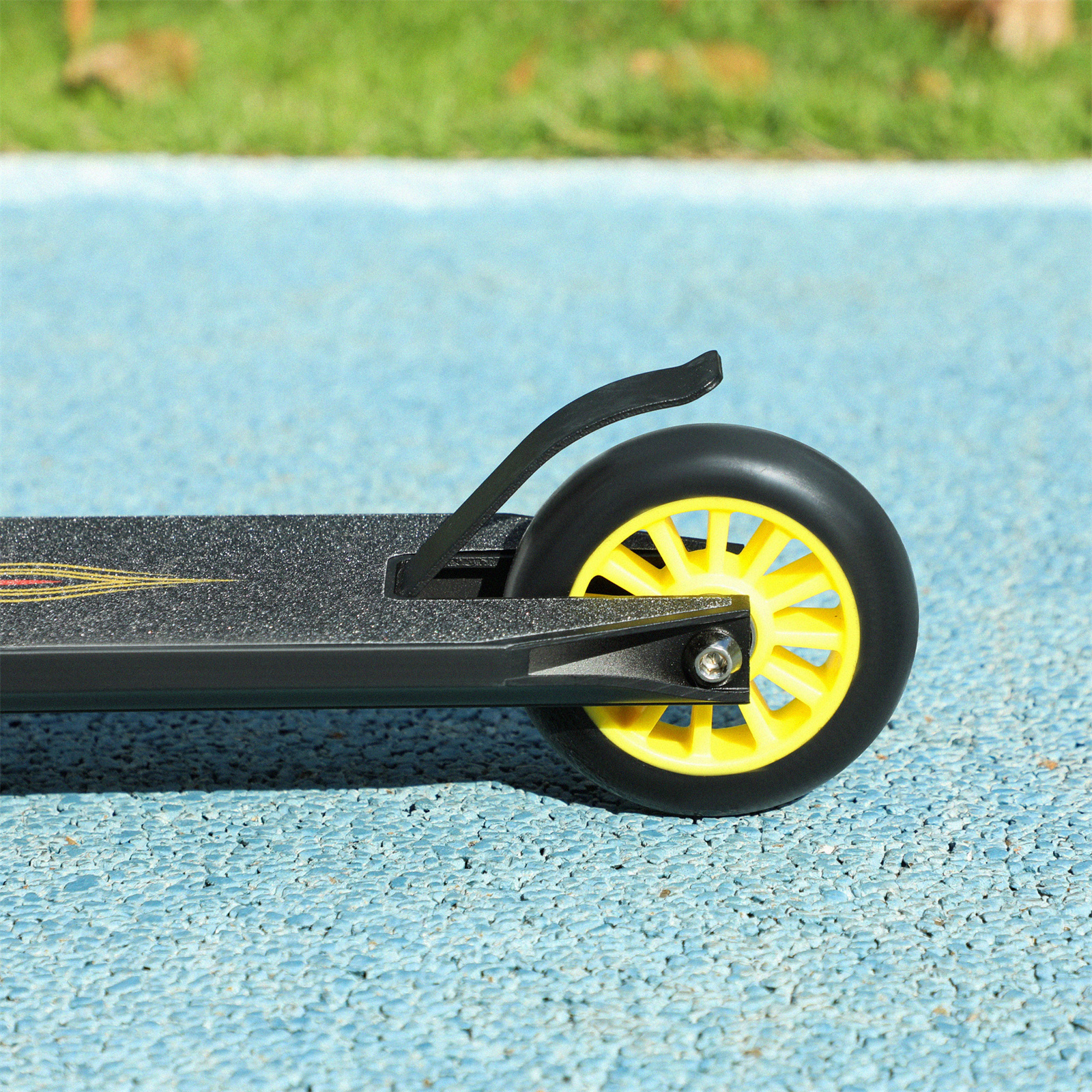 Ein schwarz-gelbes Roller-Rad auf blauer Oberfläche, Nahaufnahme, zeigt Rad und Deck.