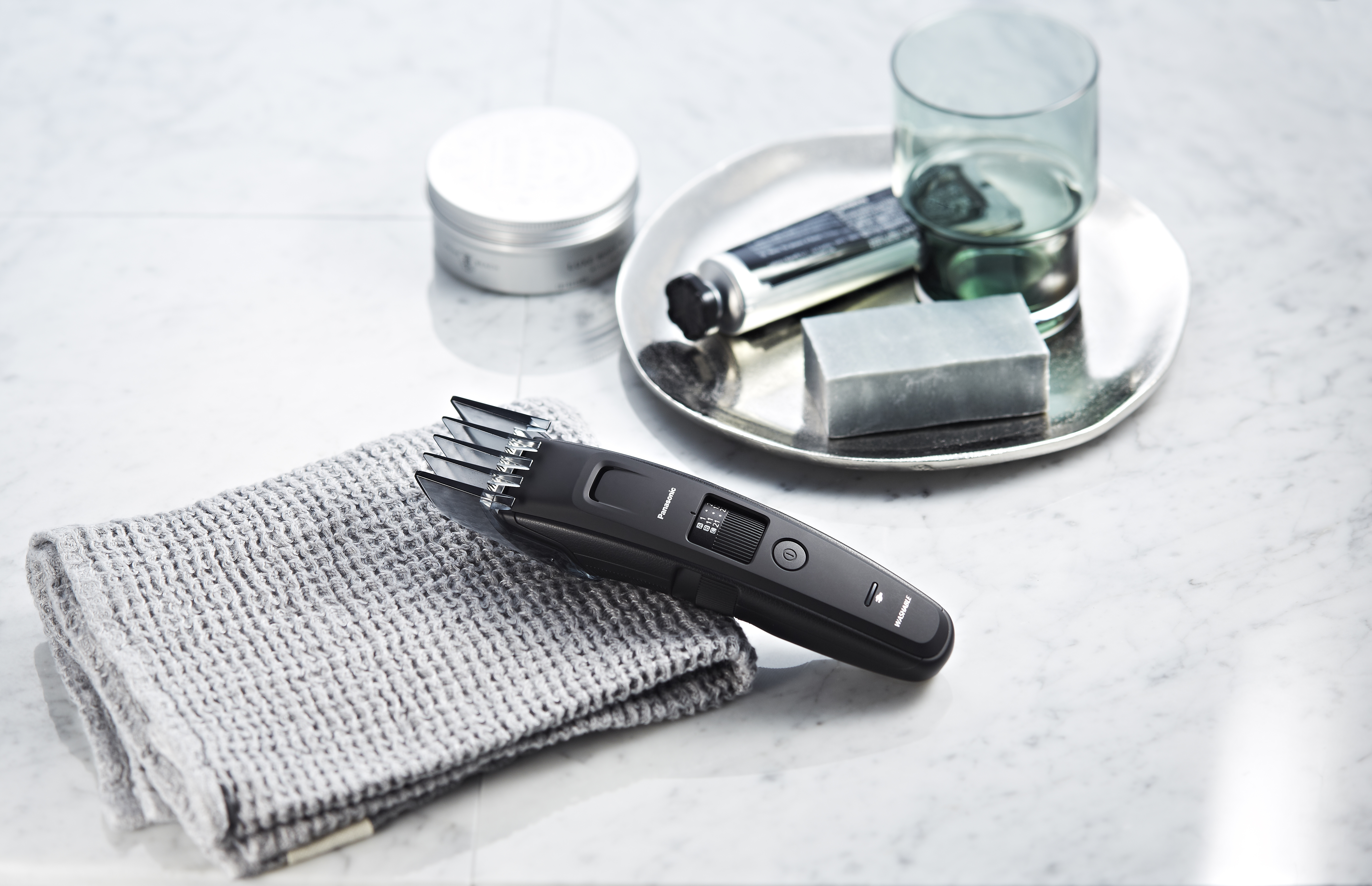 Trimmer nero, asciugamano, sapone e oggetti su marmo.