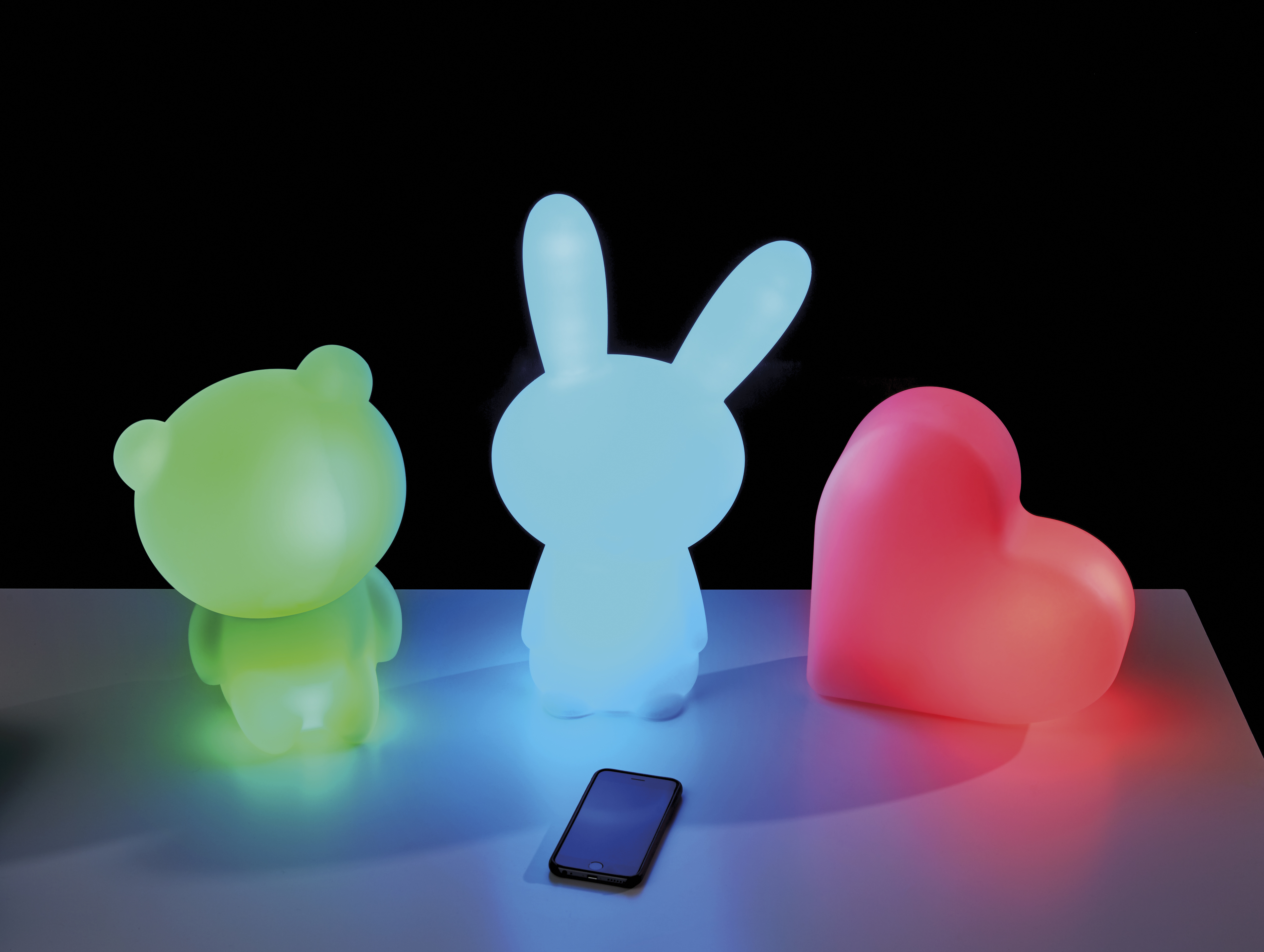 Drei beleuchtete Spielfiguren: Bär, Hase und Herz, mit einem Telefon.