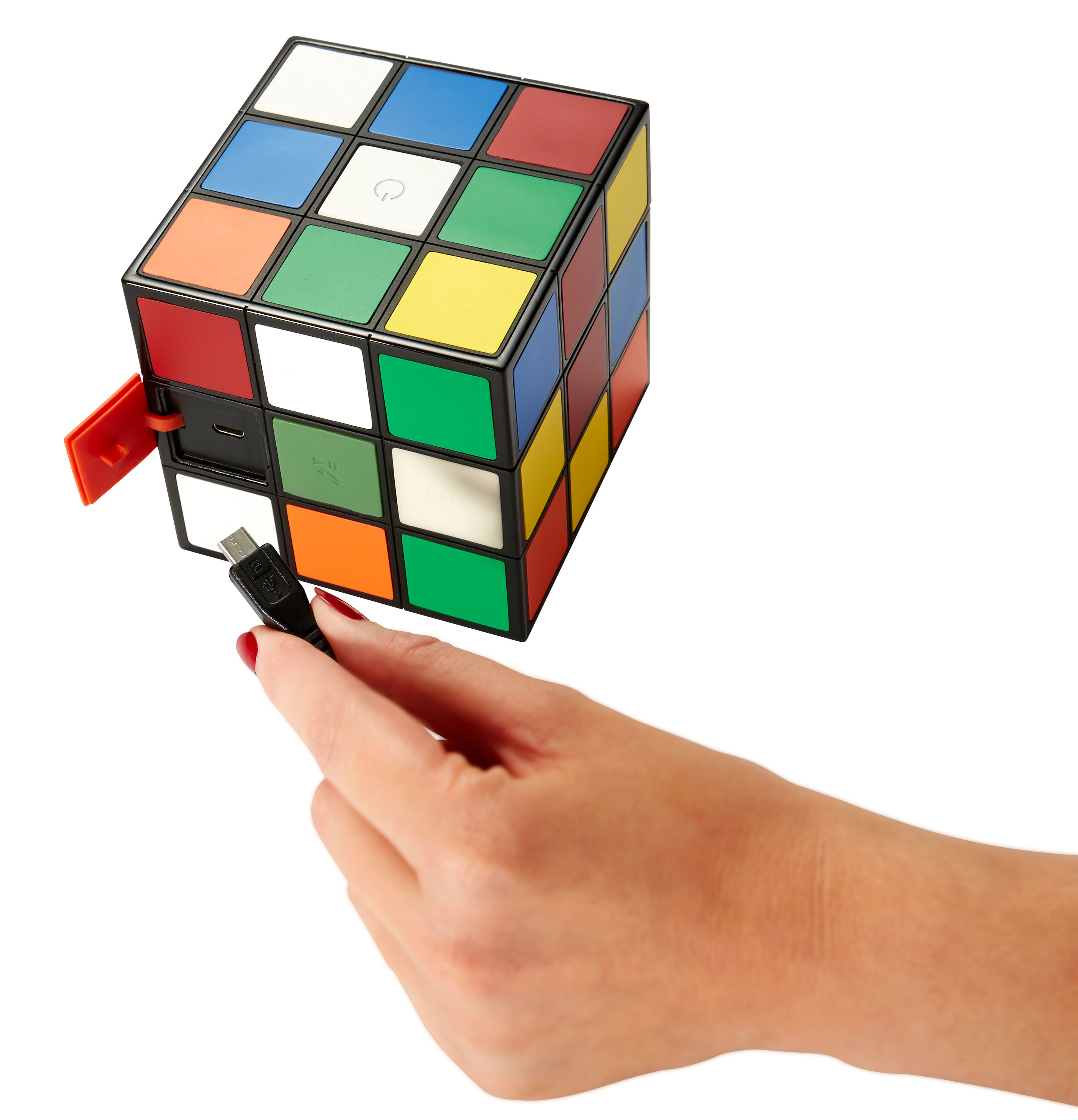 Una mano che tiene un cavo USB collegato a un altoparlante a cubo di Rubik colorato.