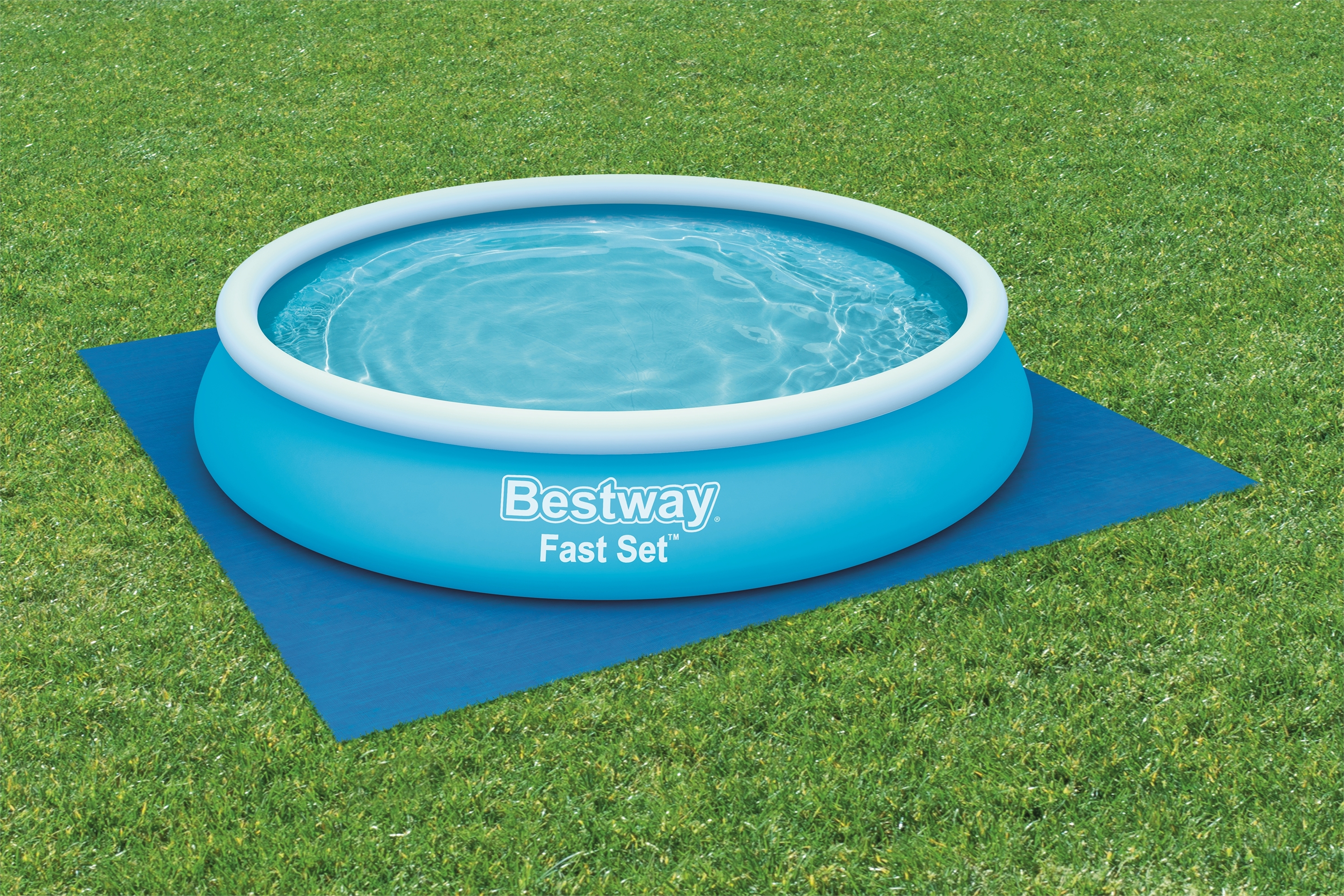 Hellblauer Pool auf blauer Matte, auf grünem Gras, Wasser drin.