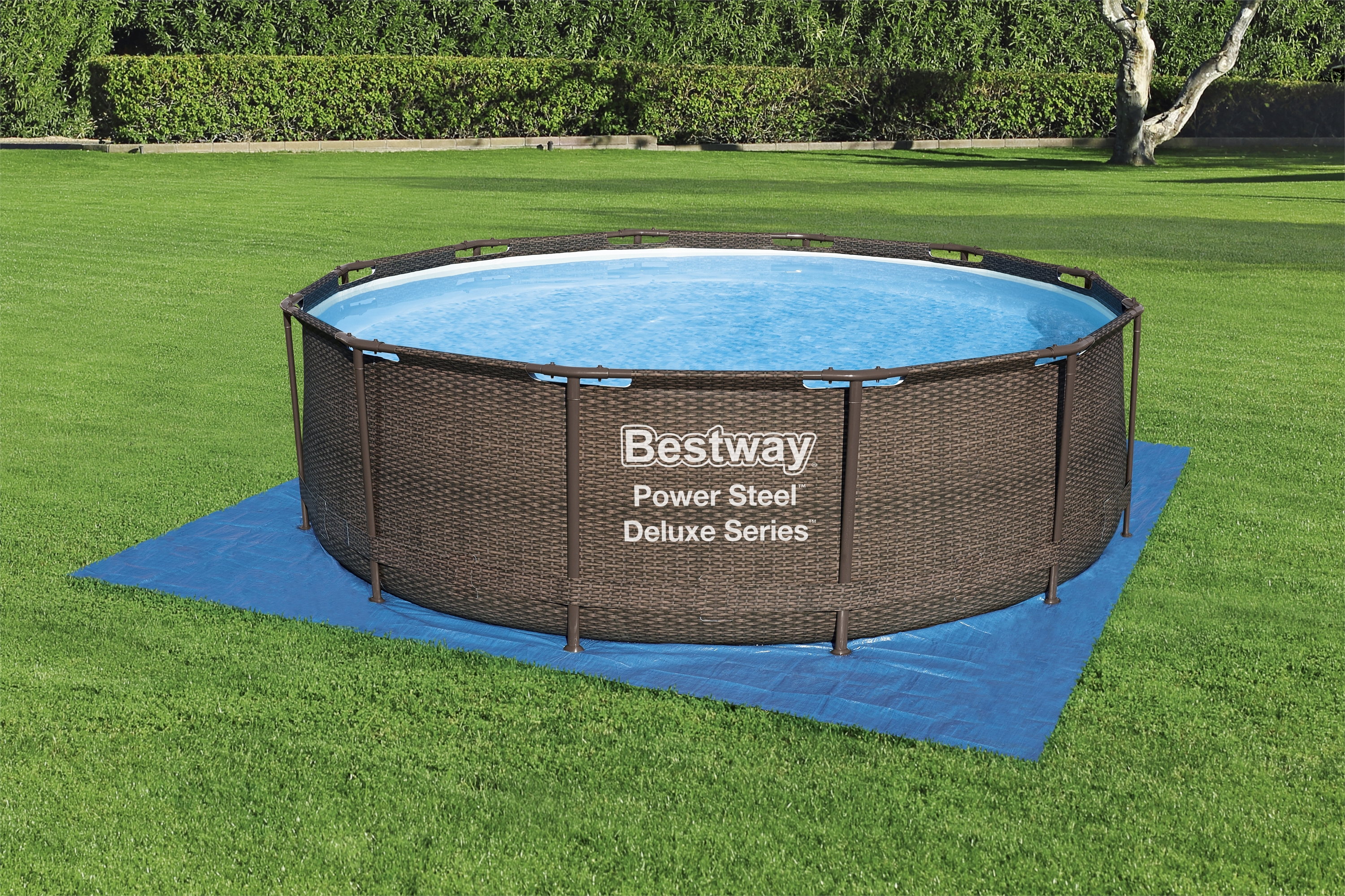 Runder brauner Pool mit Wasser, auf blauer Matte, grüner Rasen.