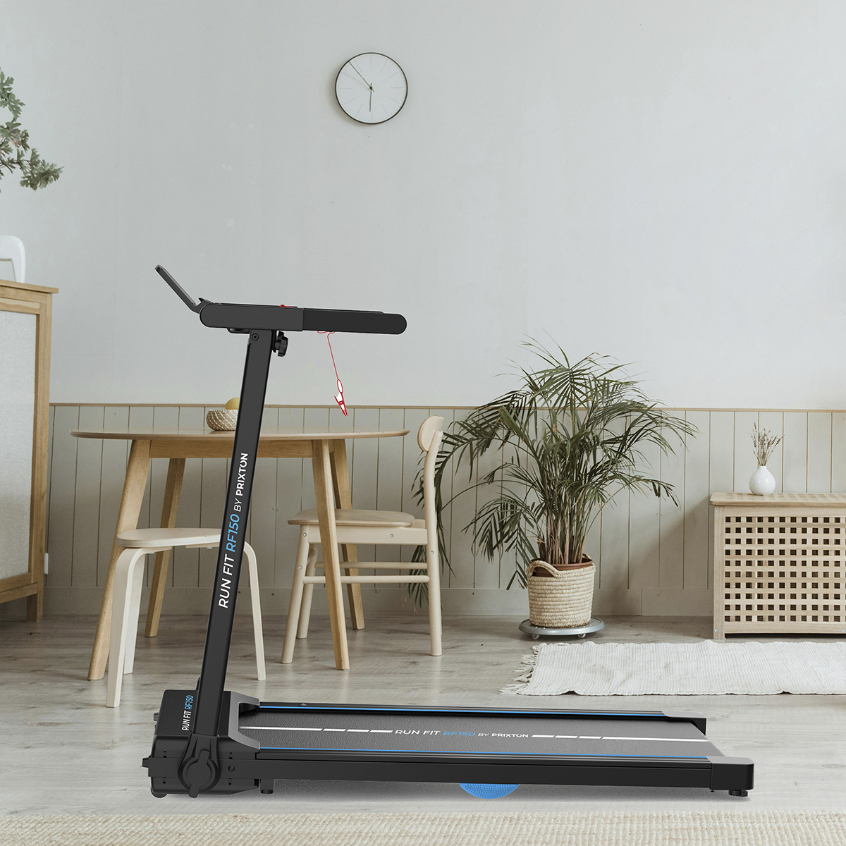 Bieżnia w pokoju ze stołem, krzesłami, rośliną i dywanem. Widoczne logo Run Fit.