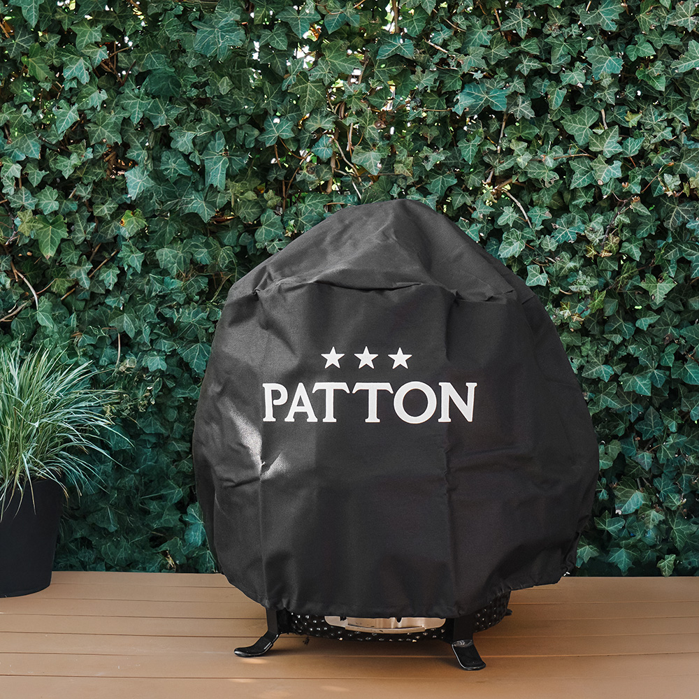 Black grill cover with white text on a wooden deck, ivy in the background.