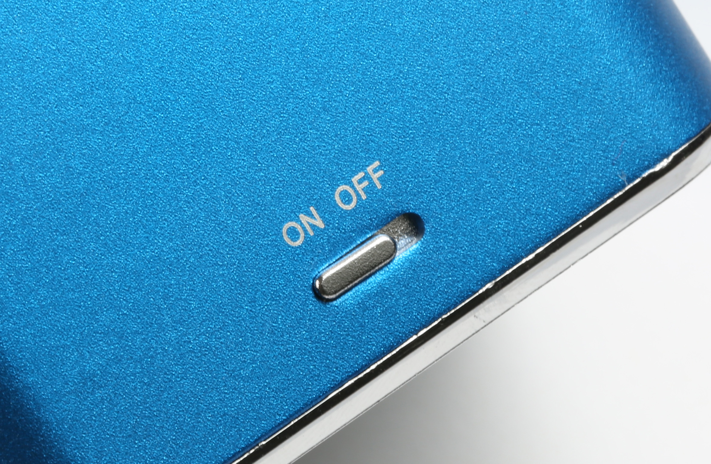 Niebieskie urządzenie z włącznikiem/wyłącznikiem. Białe tło.