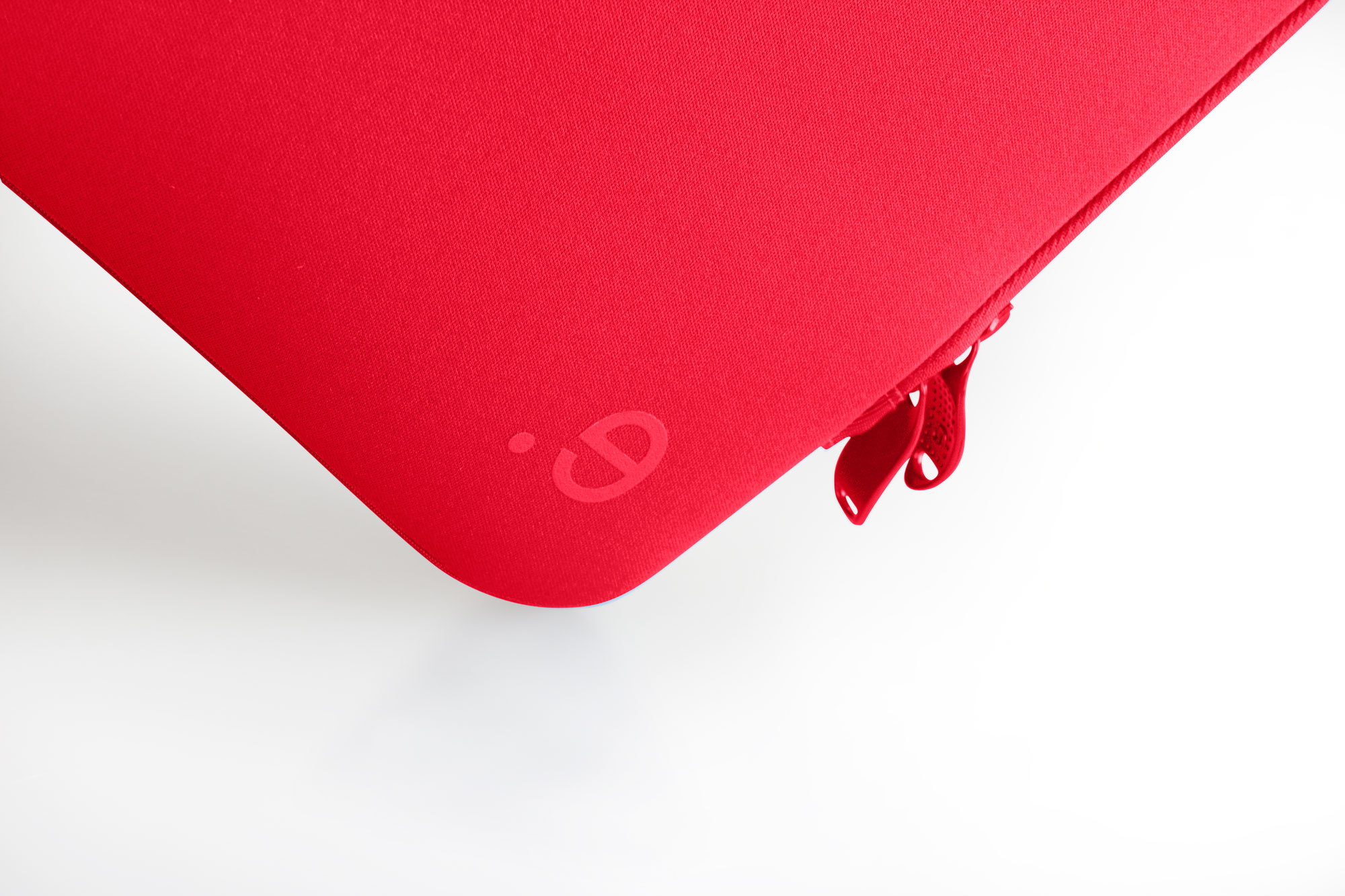 Custodia rossa per laptop con un piccolo logo sull'angolo e una cerniera. Su sfondo bianco.