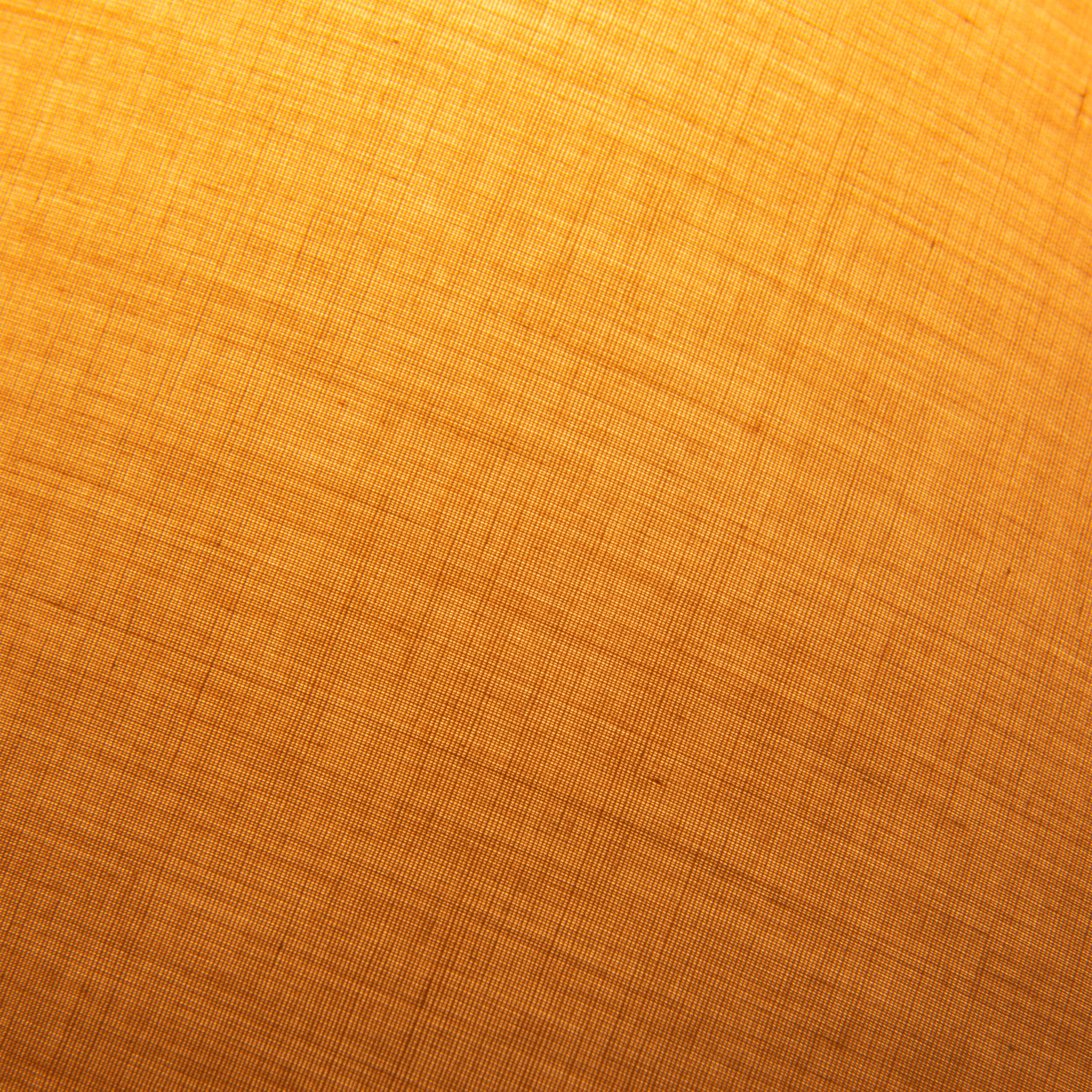 Nahaufnahme des orangefarbenen Lampenschirmstoffs. Der Stoff hat eine gewebte Textur und wird von oben beleuchtet.
