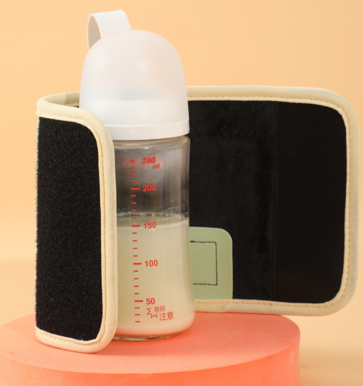 Babyflasche mit Milch in einem schwarzen und beigefarbenen isolierten Bezug mit Klettverschluss.