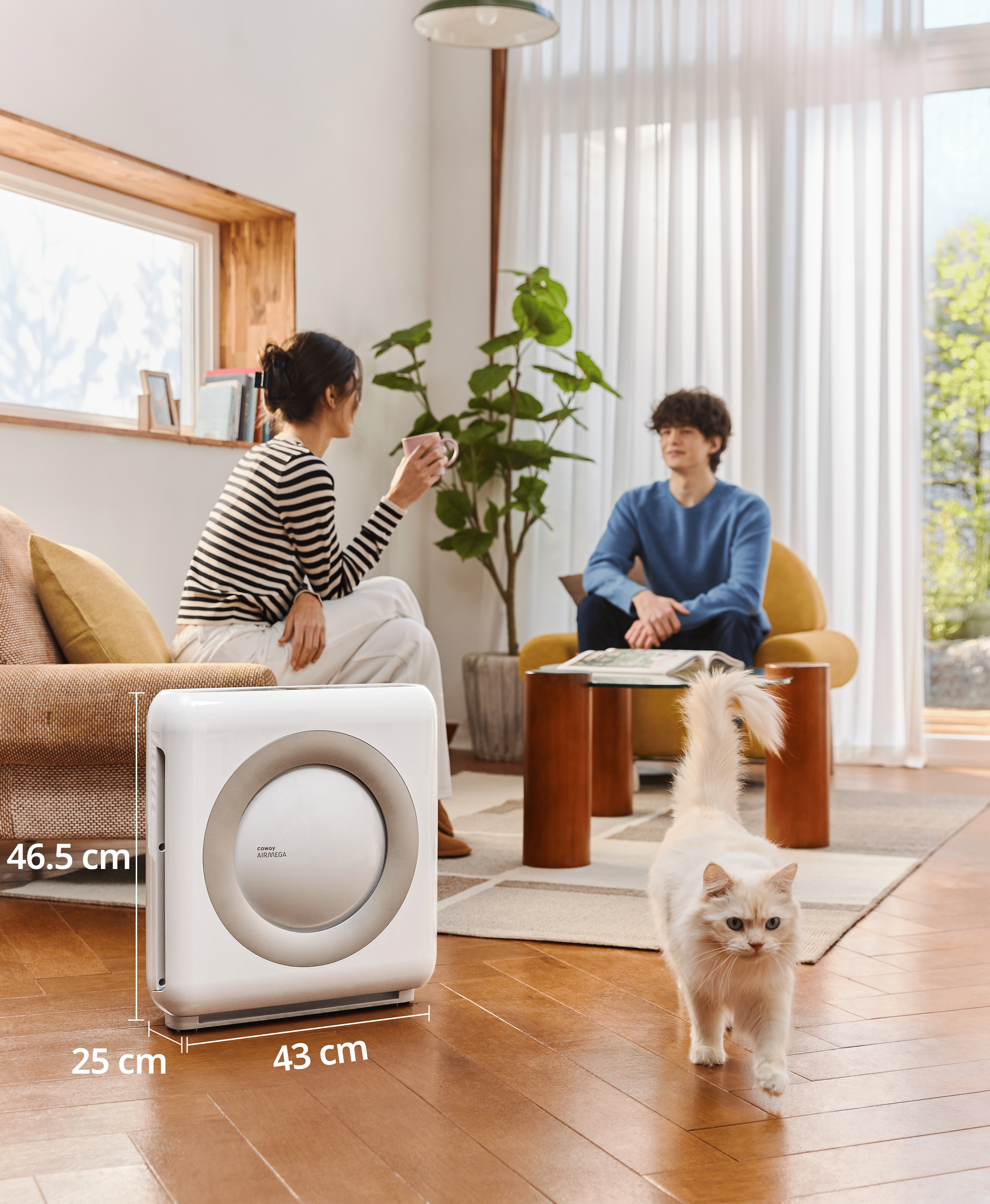 Wohnzimmer mit Personen, Luftreiniger und Katze. Der Reiniger ist weiß, die Katze ist weiß.