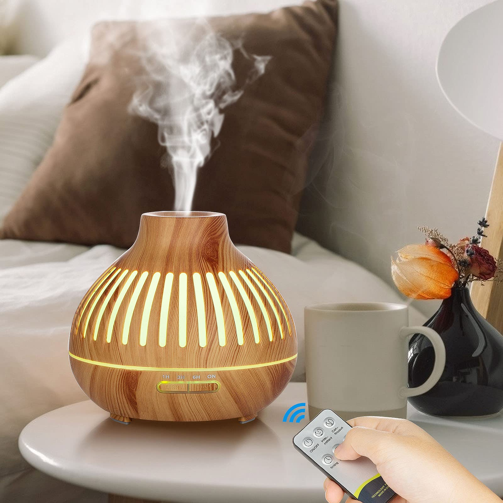 Holz-Aromadiffusor mit Dampf, auf einem Nachttisch mit Dekoration und Fernbedienung.