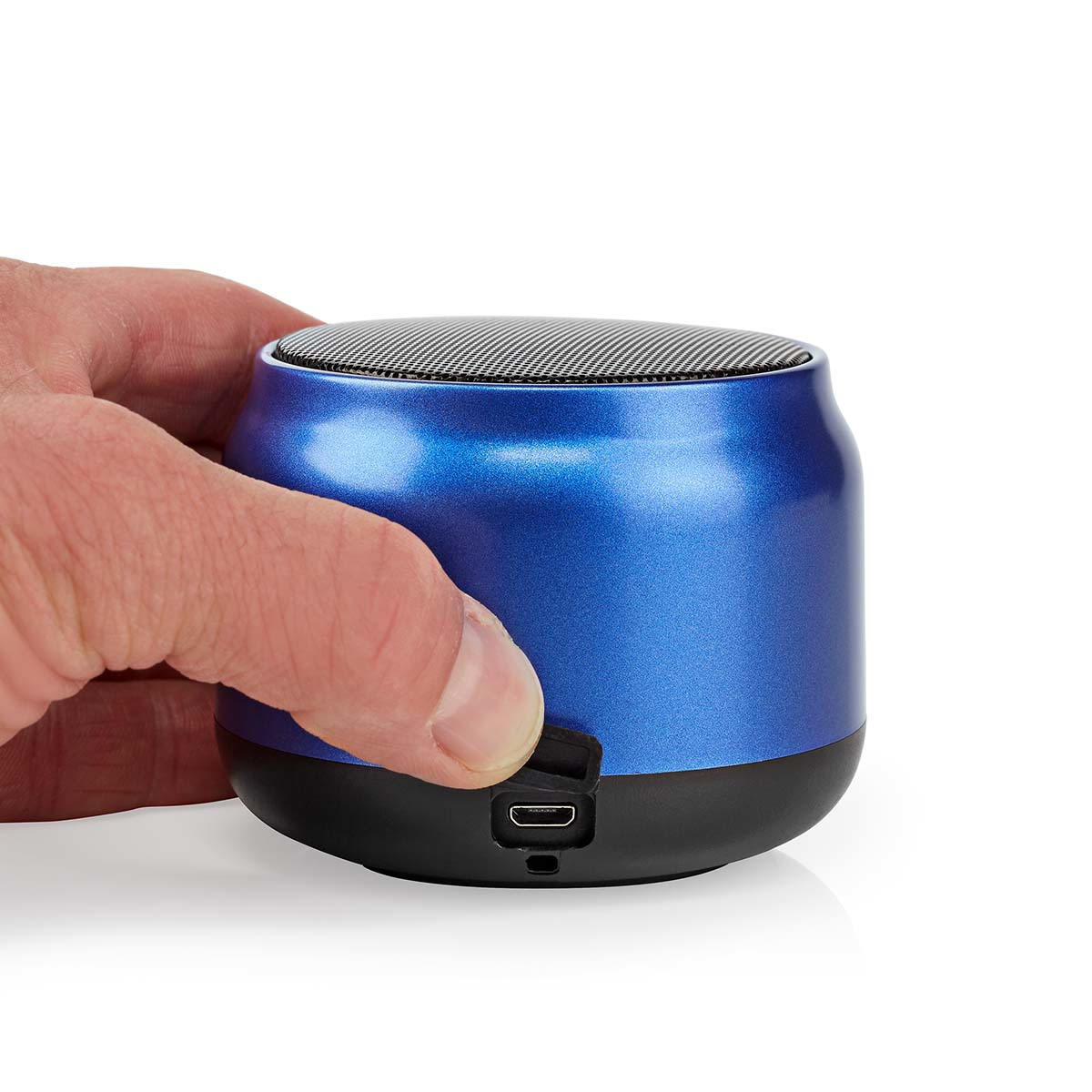 Eine Hand hält einen kleinen blauen Lautsprecher mit schwarzem Boden auf weißem Hintergrund.