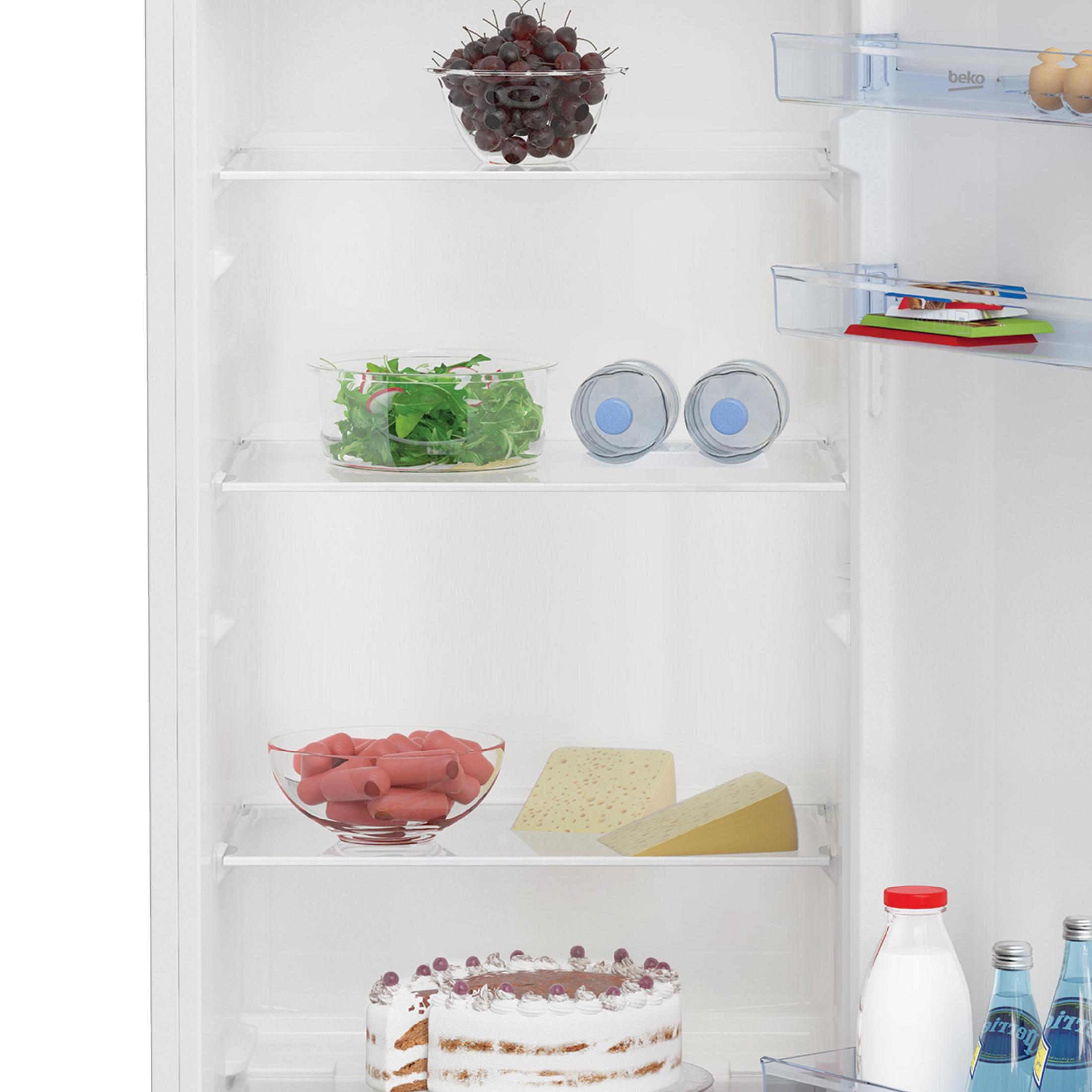 Interno del frigorifero: uva, insalata, acqua, salsicce, formaggio, torta, latte e bevande.