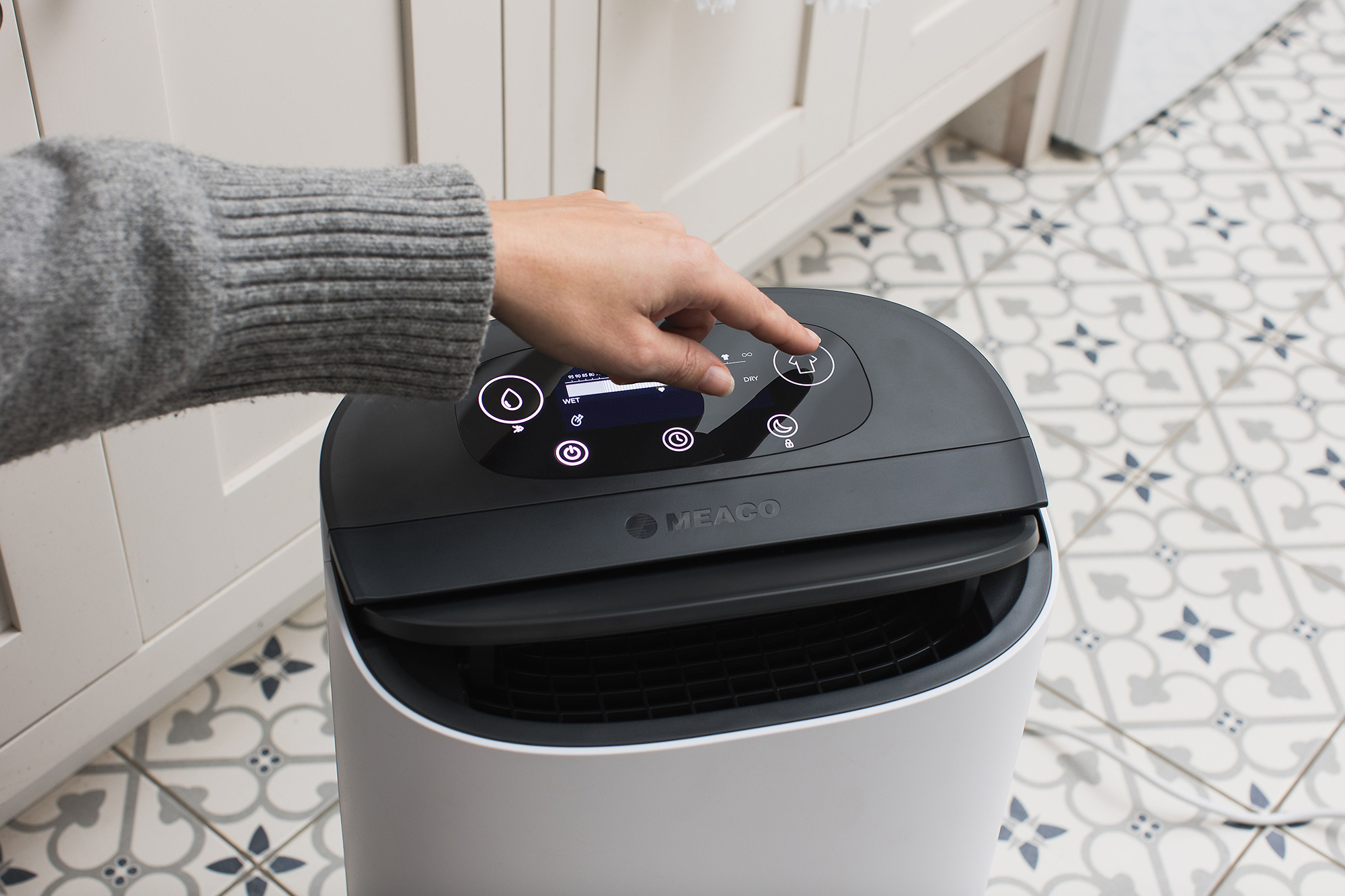 Ręka naciska przycisk na biało-czarnym oczyszczaczu powietrza.