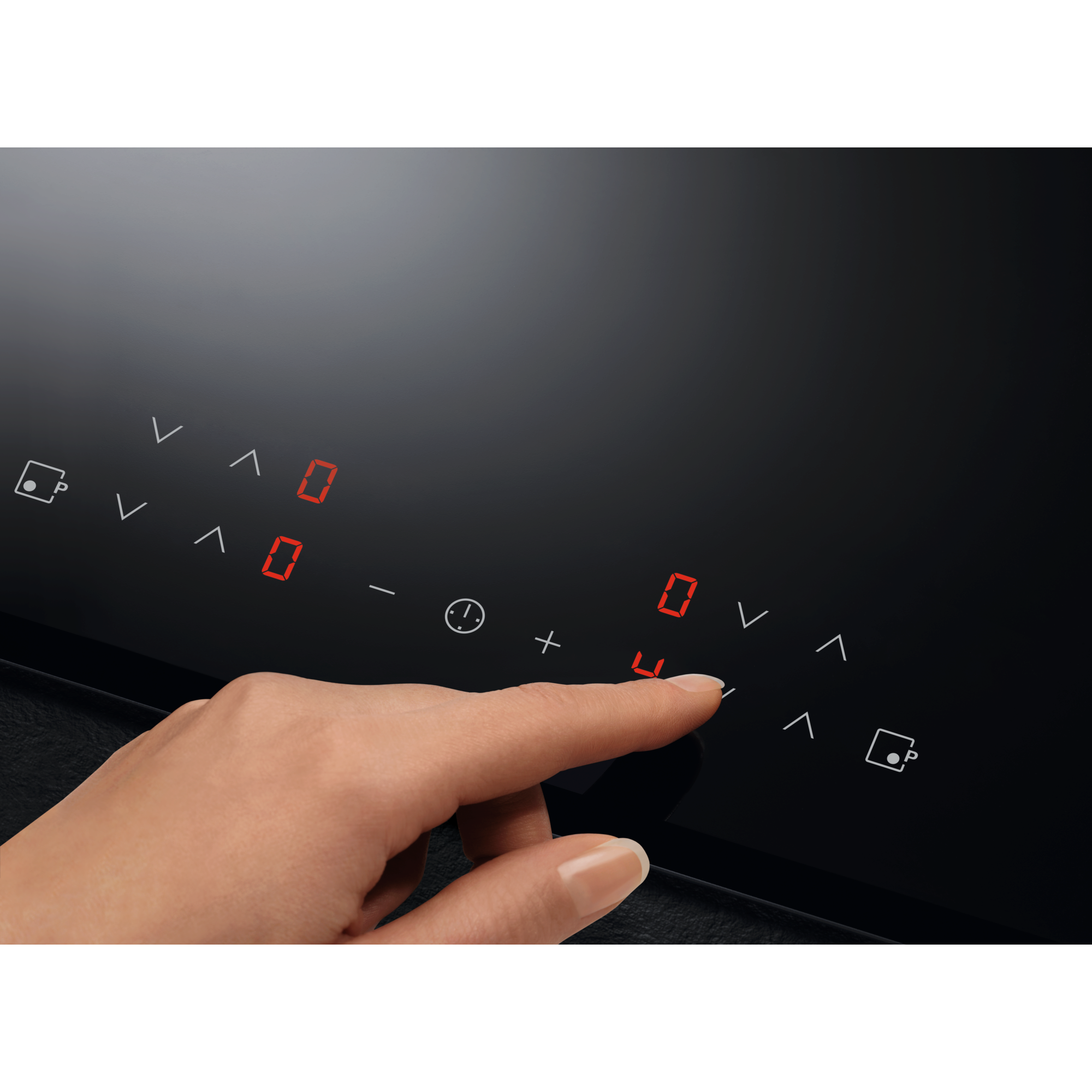 Una mano tocca un piano cottura a induzione nero con display digitale rosso illuminato.