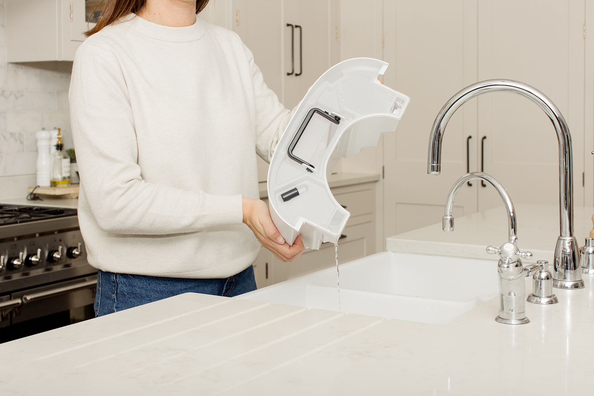 Kobieta trzymająca biały plastikowy element nad zlewem.