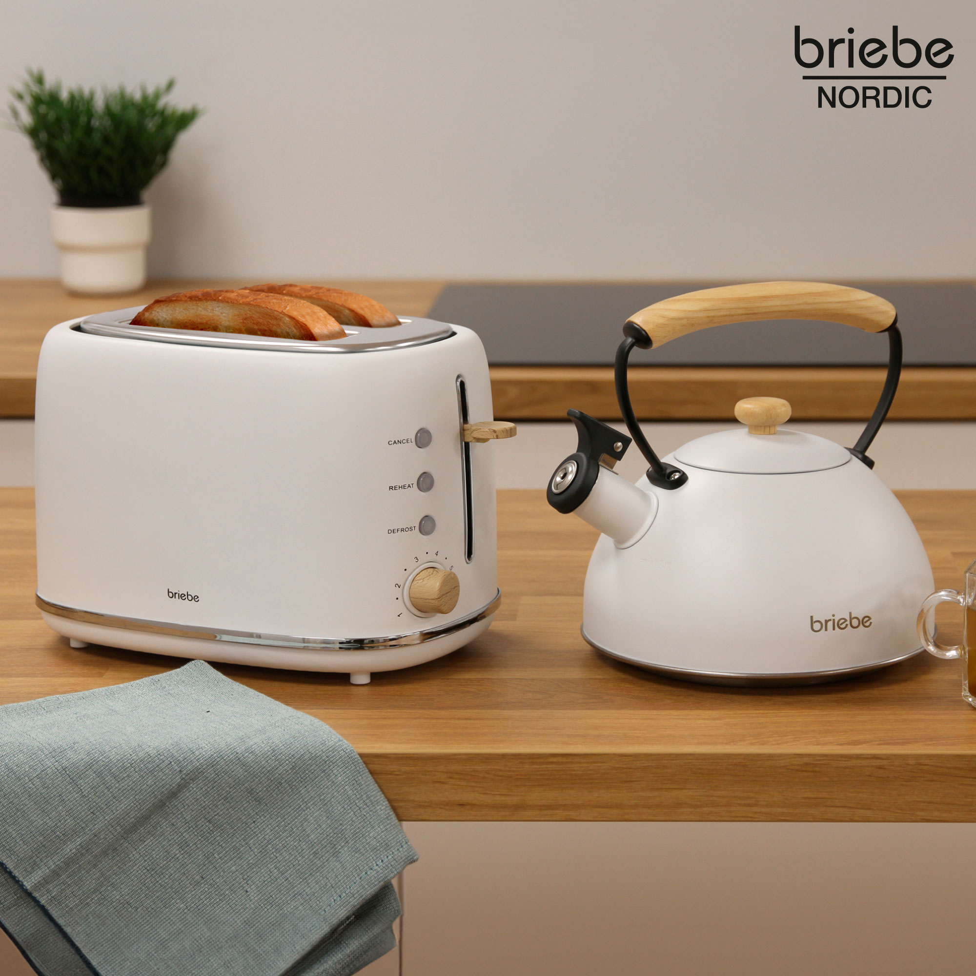 Ein Toaster mit Brot und ein Wasserkocher auf einer Holzoberfläche, mit einem blauen Tuch.