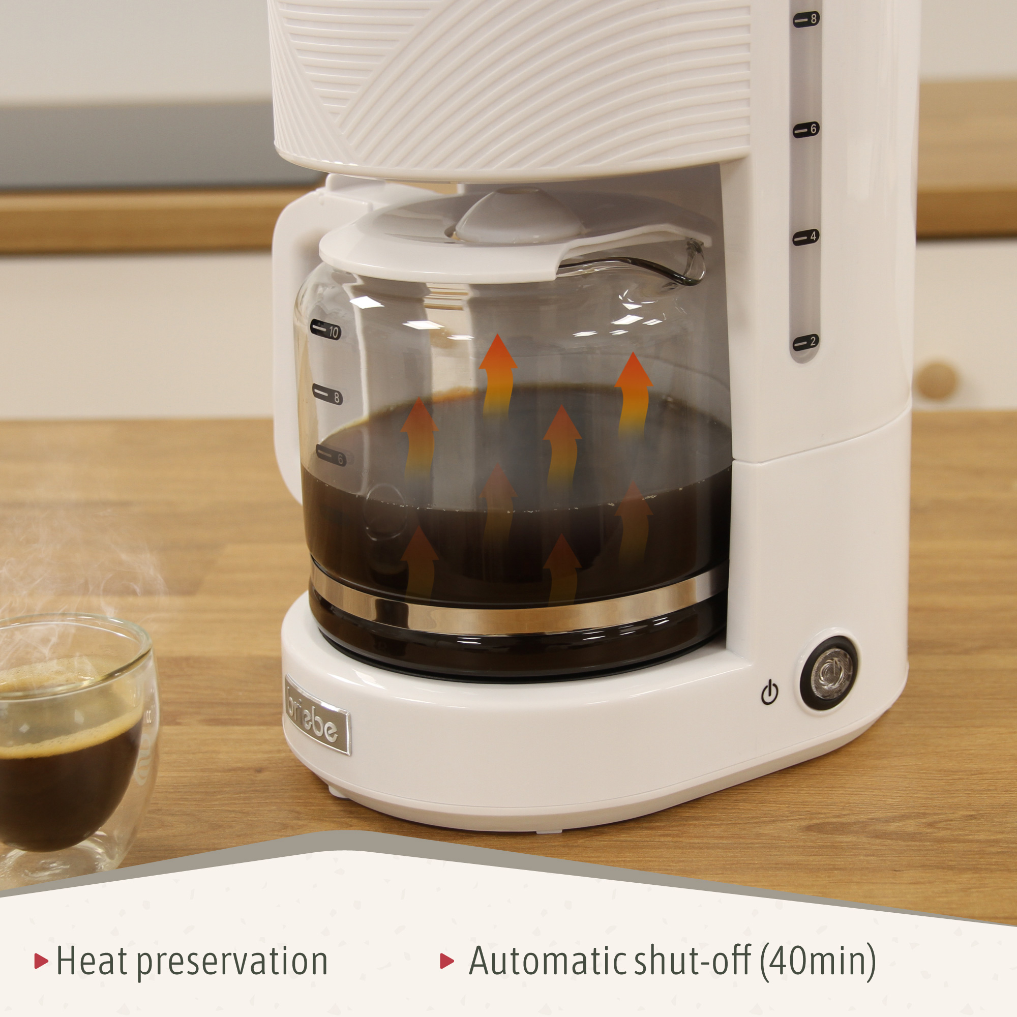 Weißer Kaffeeautomat beim Brühen. Kaffee wird gegossen. Glas Kaffee links.
