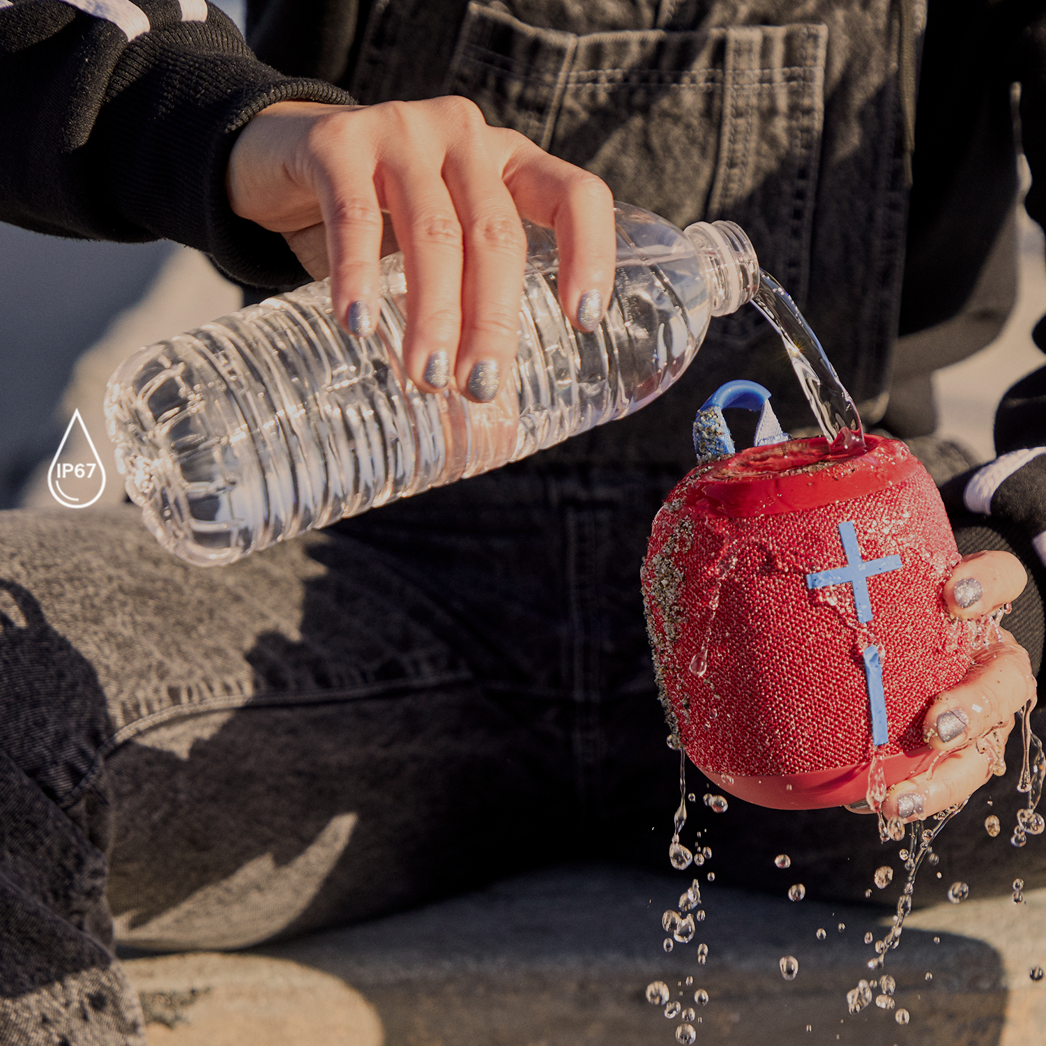 Osoba polewa czerwoną głośnik wodą. Rozpryski wody. Etykieta IP67.