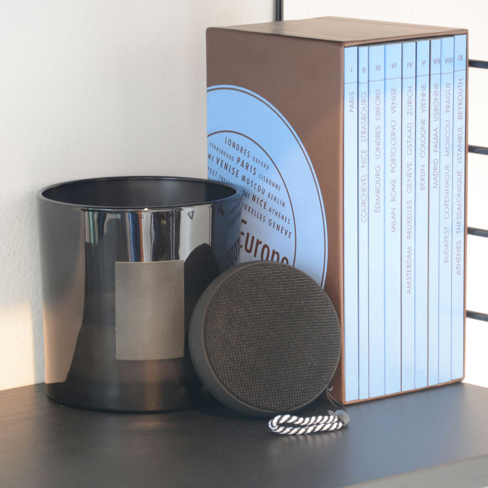 Czarny świecznik, głośnik i książki na półce.