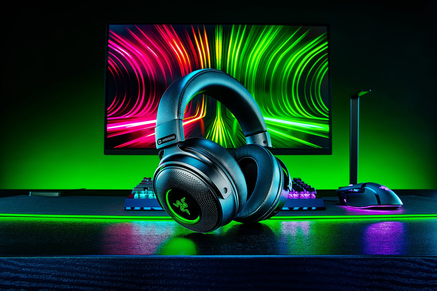 Auriculares gaming negros, teclado y ratón, fondo verde.