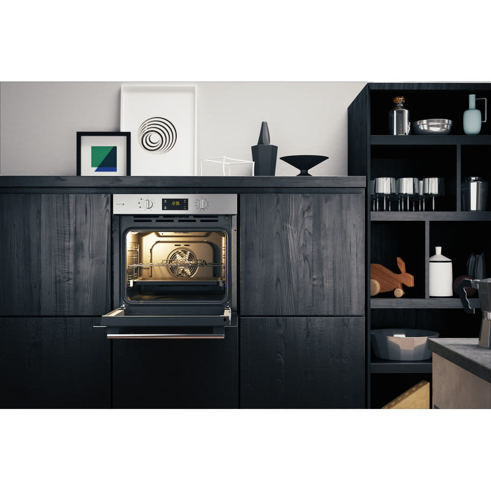 Un forno integrato in un mobile nero, la porta è aperta, che mostra le luci interne.
