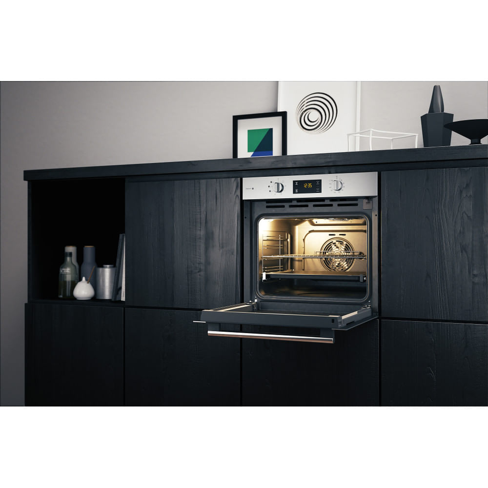 Forno in una cucina. Porta aperta. Mobili in legno. Piano di lavoro nero. Luce all'interno del forno.