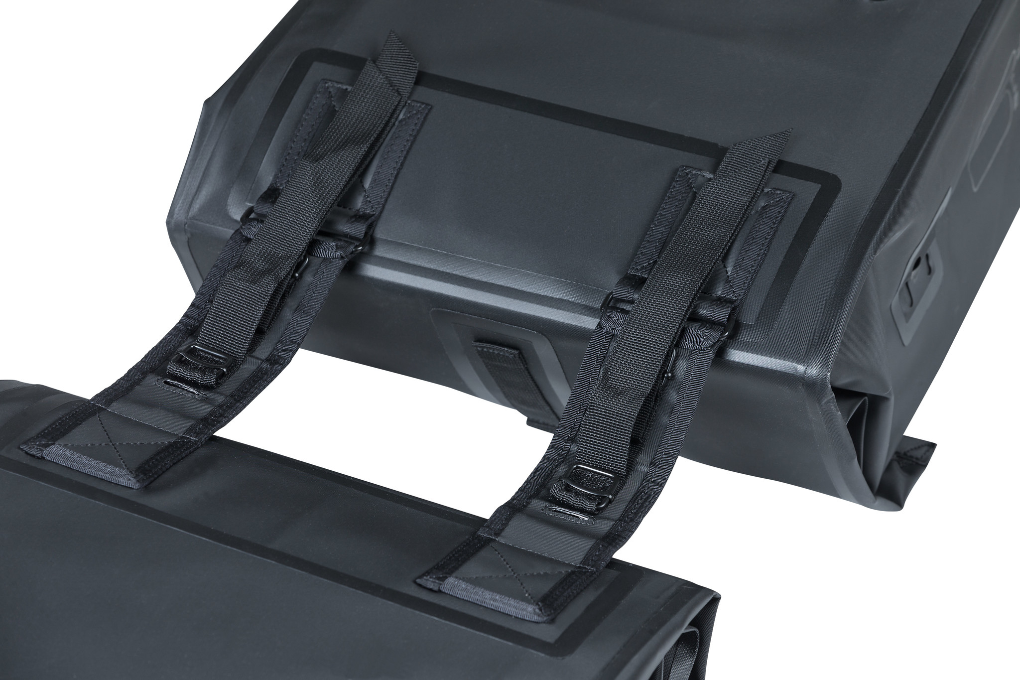 Zbliżenie czarnych sakw rowerowych z paskami i klamrami na białym tle.