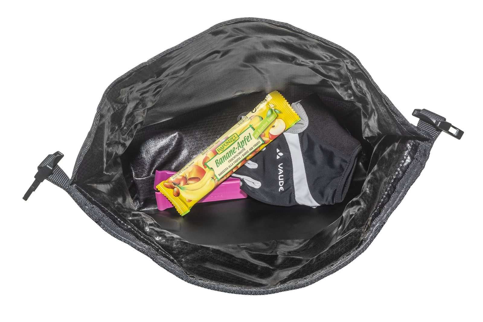 Otwarta czarna torba z przekąskami w środku. W środku batonik bananowo-jabłkowy, różowy batonik i akcesorium Vaude.