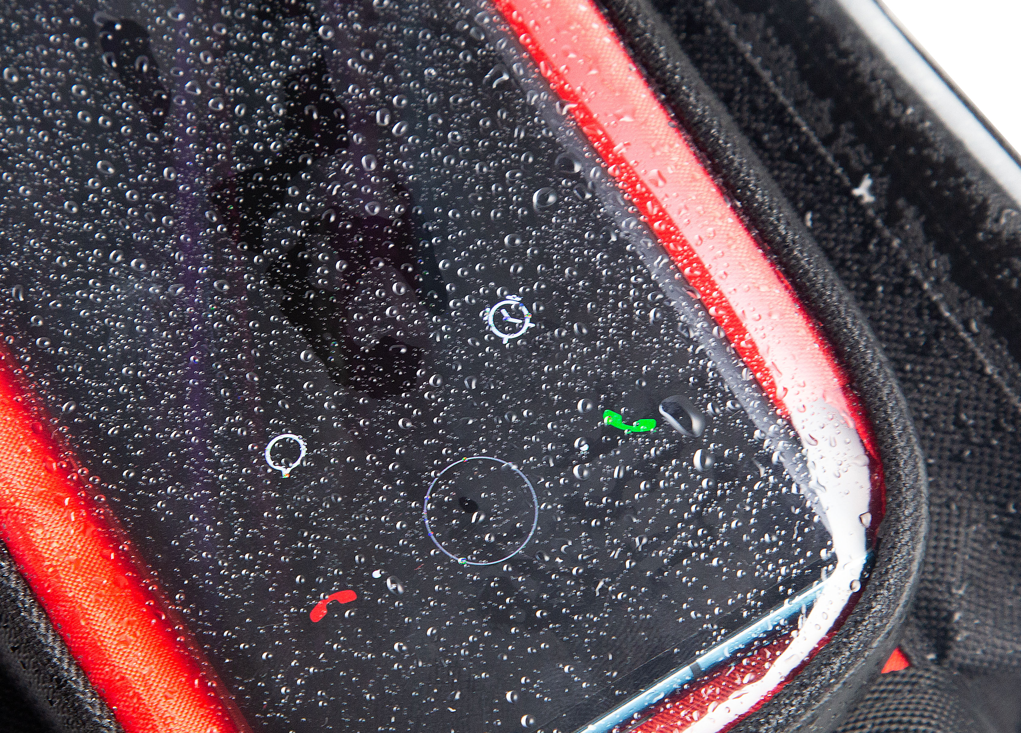 Zbliżenie na ekran telefonu pokryty kroplami wody z ikonami aplikacji.