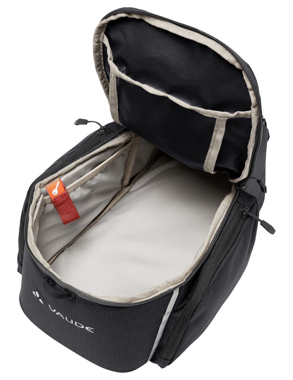 Częściowo otwarty czarny plecak z wieloma kieszeniami i logo Vaude.