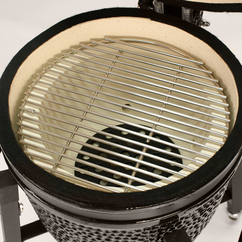 Close-up of a black Kamado-style grill with a stainless steel grill grate.
