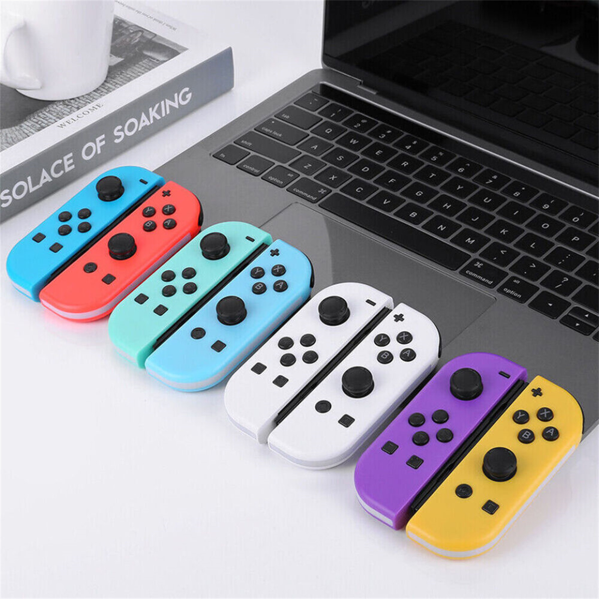 Sechs farbige Gamecontroller auf einem Laptop. Die Controller sind blau, rot, grün, weiß, lila und gelb.