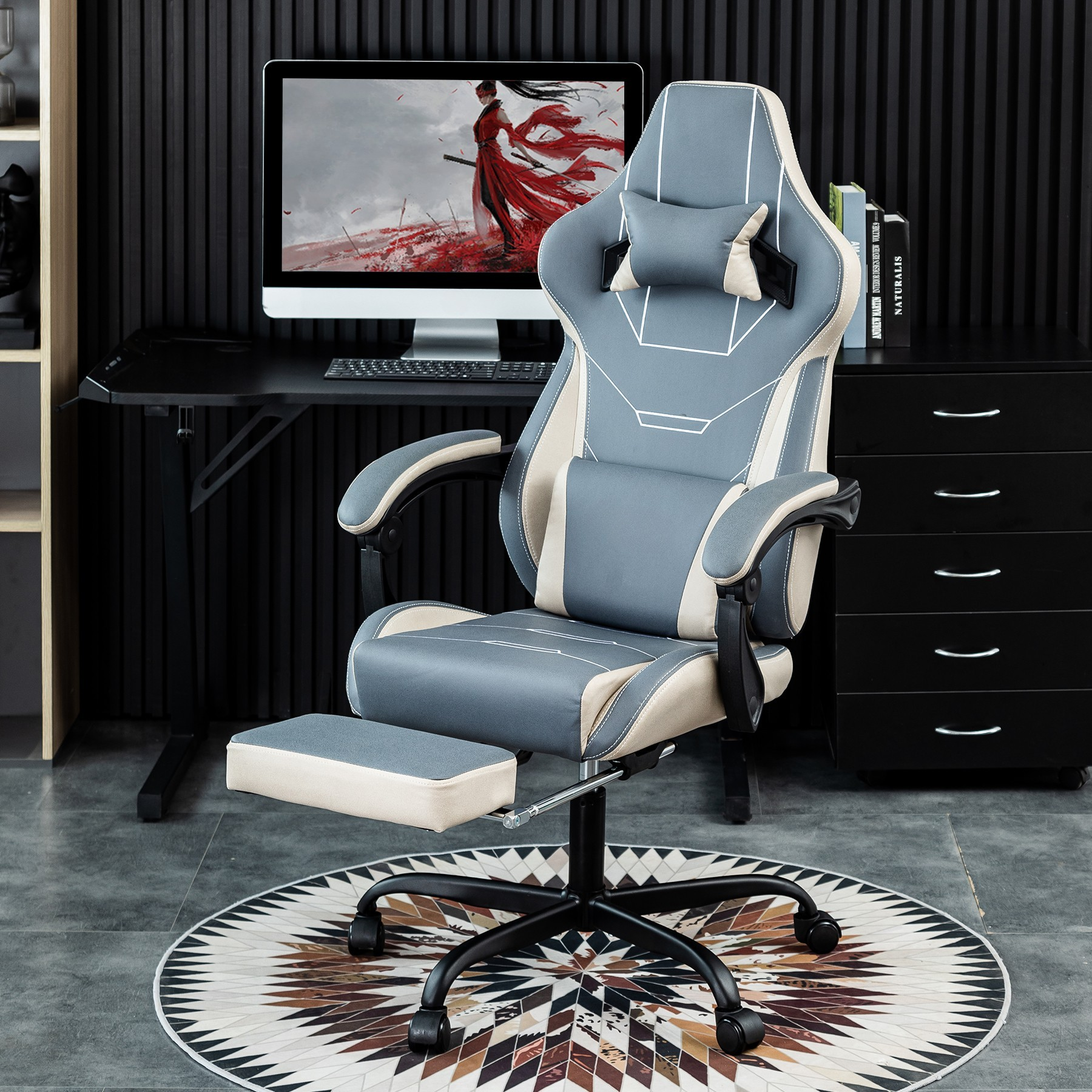 Gaming-Stuhl mit Fußstütze, grau und weiß, in einem Raum mit Computer und Schreibtisch.