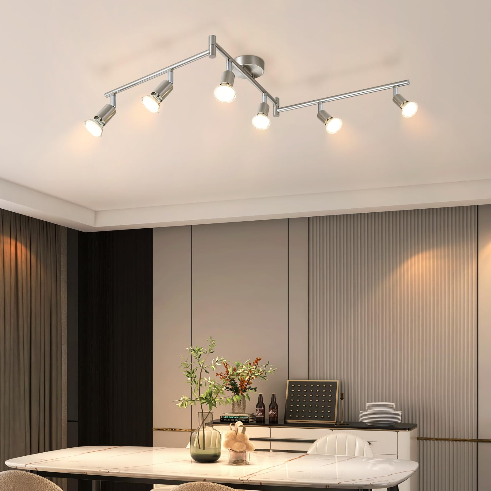 An der Decke montierte Schienenbeleuchtung mit sechs Lichtern, die ein Esszimmer beleuchten. Innenraum mit Tisch und Dekoration.